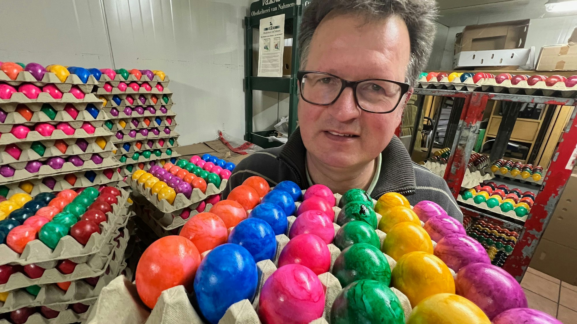 Das Bild zeigt den Landwirt Martin Füngeling aus Hürth mit mehreren Brettern bunter Eier.