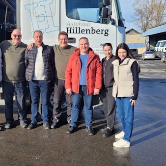 Eine Gruppe von Menschen steht untergehakt vor einem Lastzug im ukrainischen Butscha.
