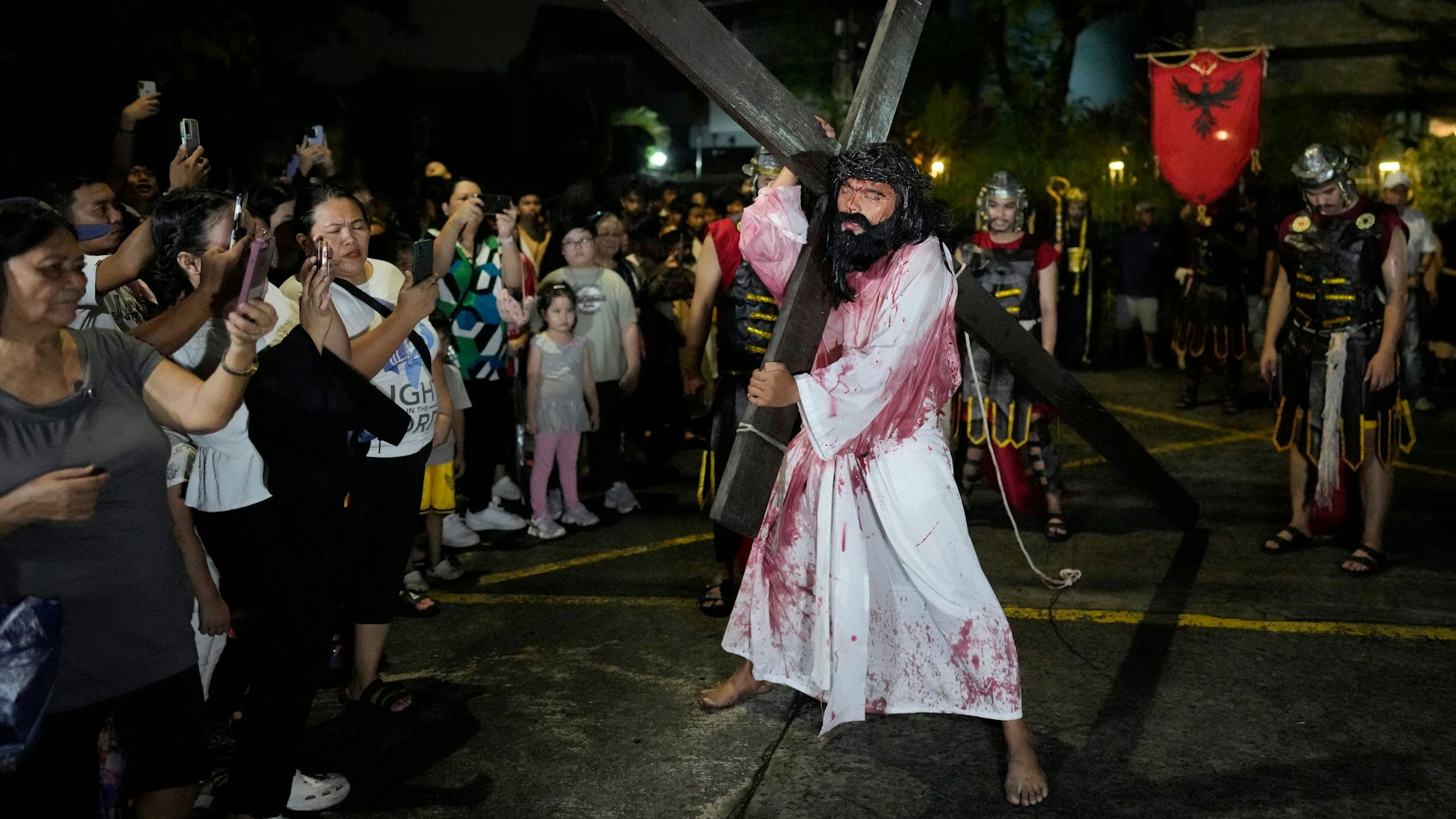 Dorfbewohner fotografieren einen Mann, der die Rolle von Jesus Christus spielt, während eines Theaterstücks zur Feier der Karwoche.