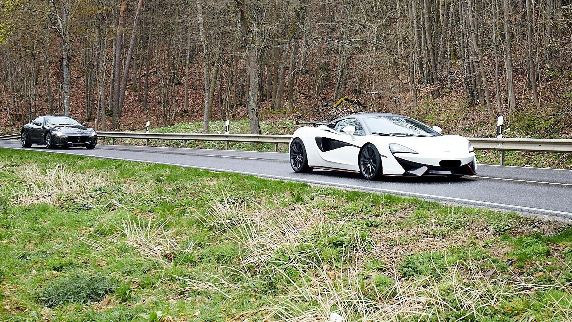 Ein weißer und ein schwarzer Sportwagen fahren hintereinander über eine Straße.