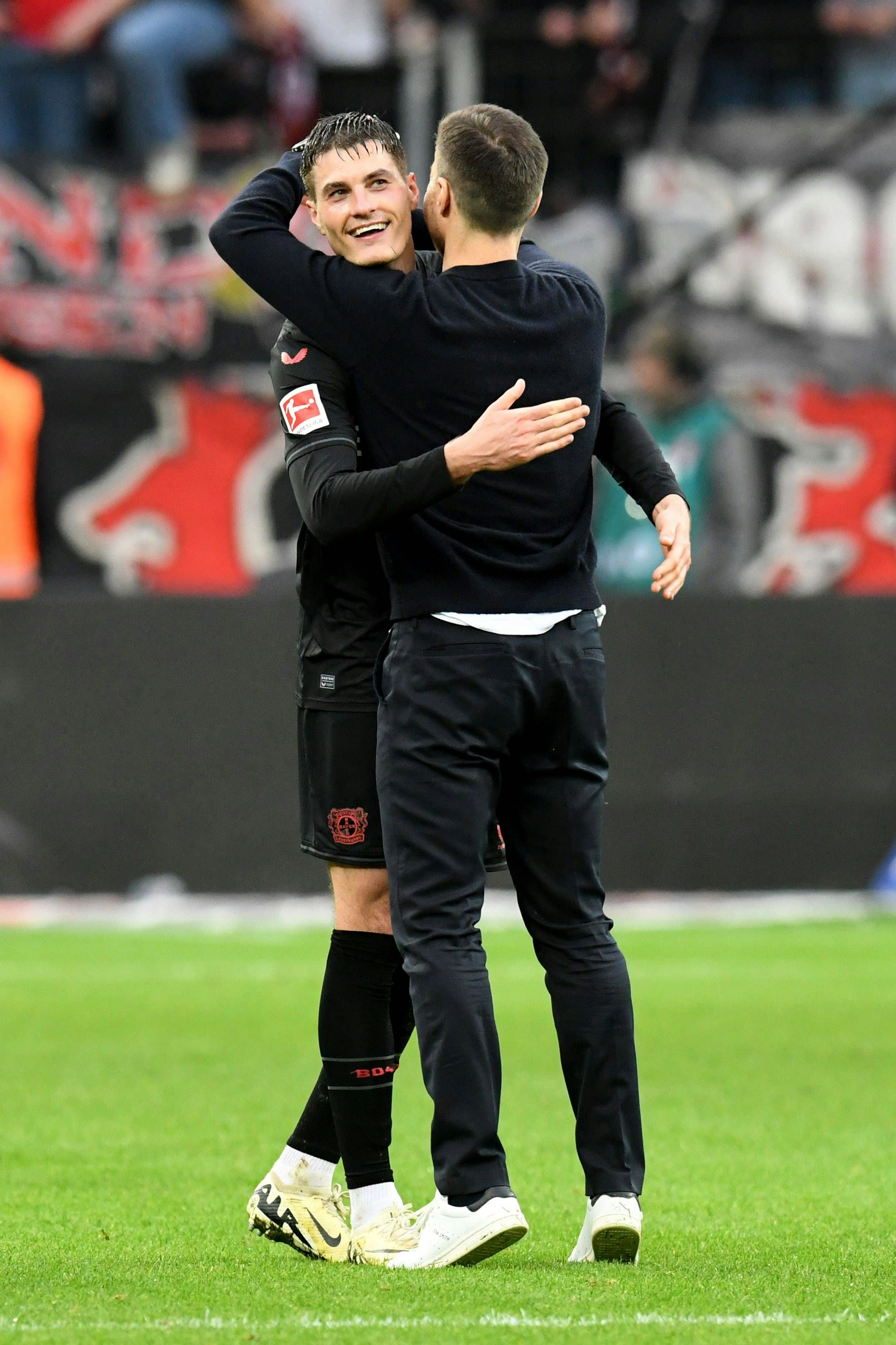 Zwei Männer umarmen sich auf einem Fußballplatz.