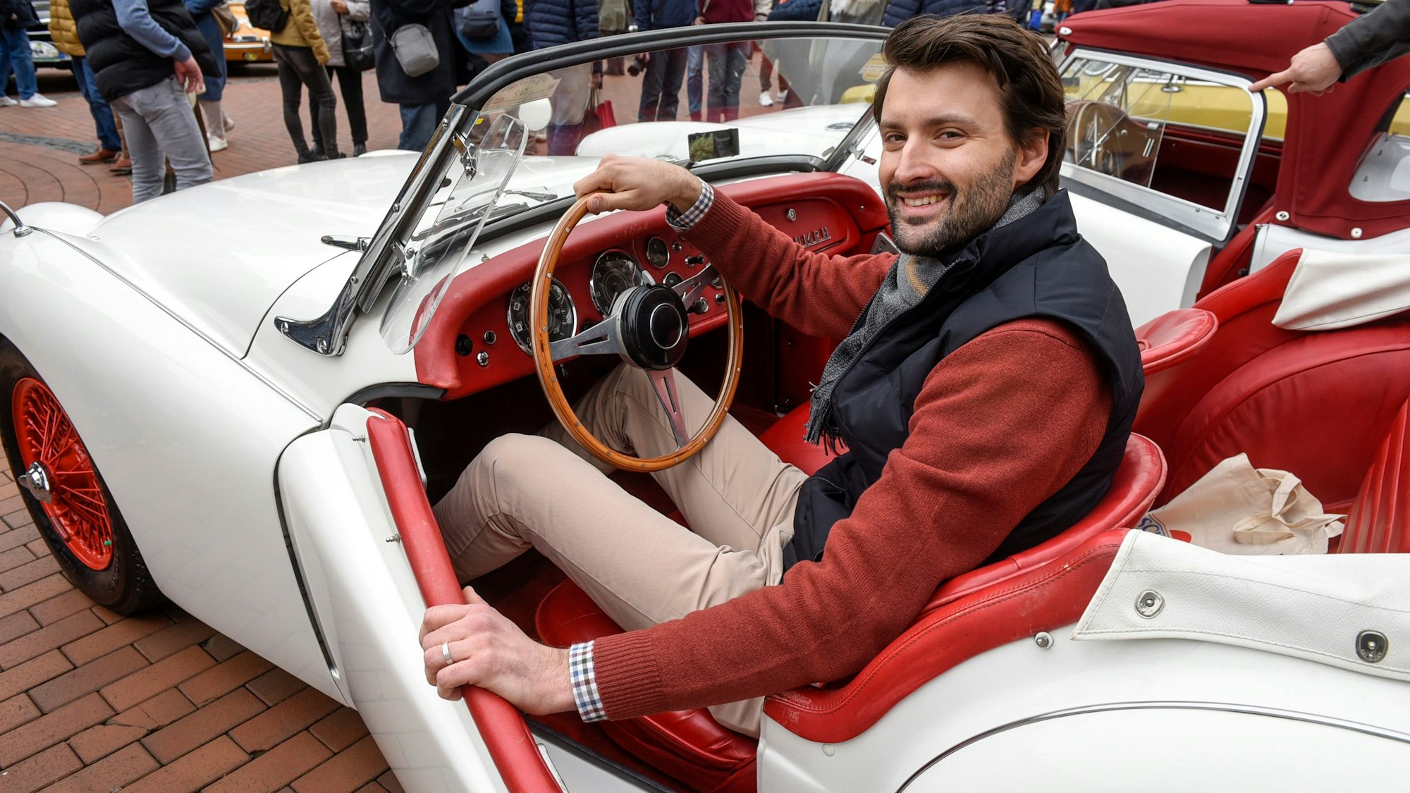 Zu sehen ist Fahrer Dominik Trager in seinen offenen, weißen Triumph TR 3.
