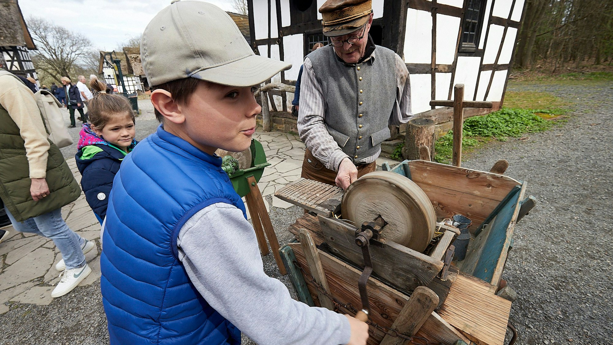 Ein Junge und ein Herr stehen an einem Messerschleifgerät.