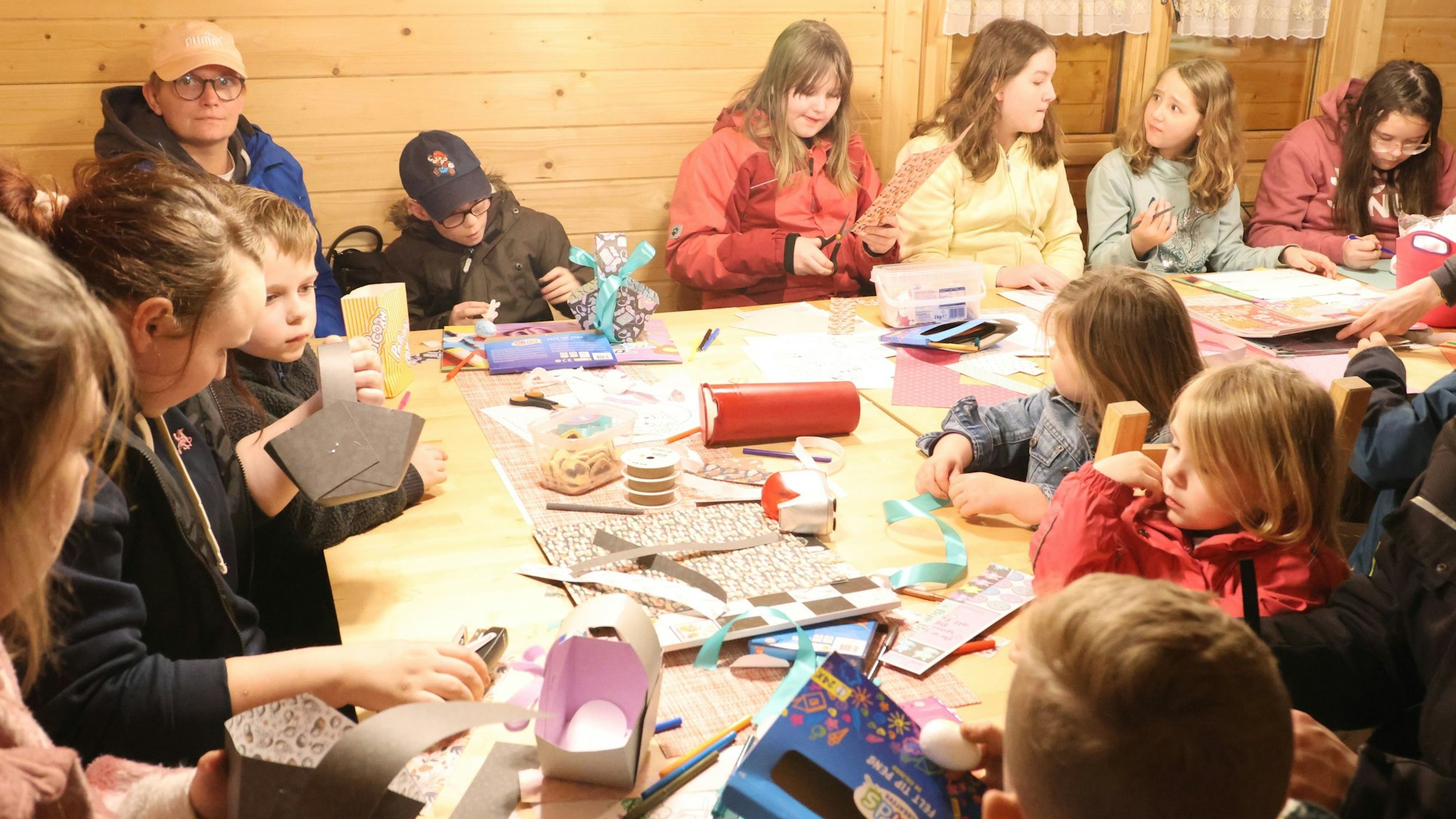 Zu sehen sind Erwachsene und Kinder, die mit Pappe basteln.