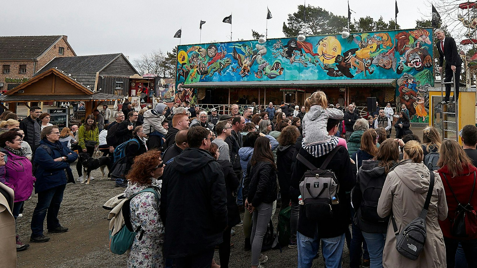 Zahlreiche Besucher stehen in Kommern beim Jahrmarkt anno dazumal vor einer Kimesbude. Rechts hinten ist ein Schausteller auf einer Leiter zu sehen.