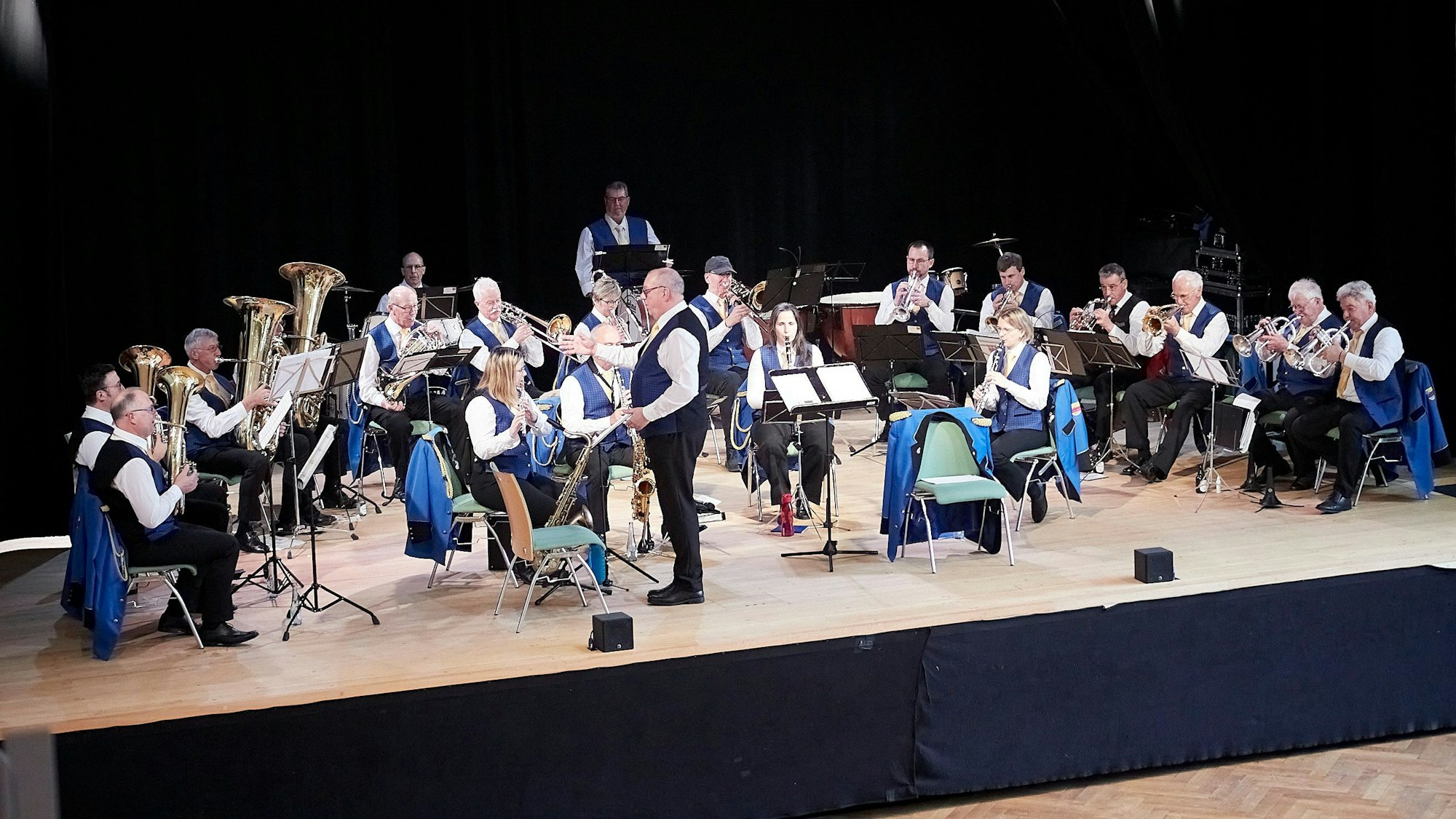 Die rund 25 Mitglieder des Orchesters präsentierten sich in blauen Westen. Der Dirigent schaut in Richtung der Bläser, um ihnen ihren Einsatz anzuzeigen.