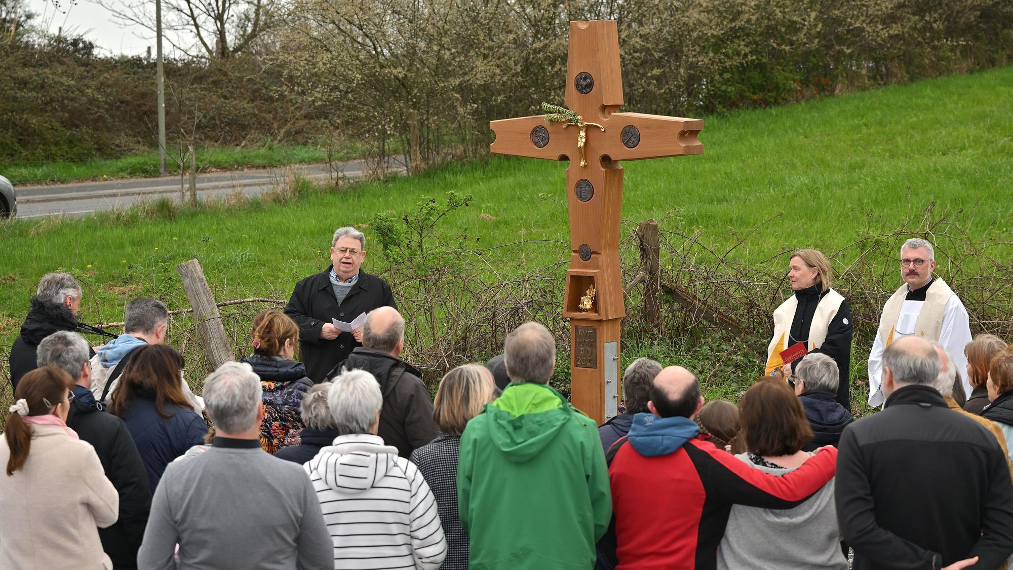 Viele Menschen stehen vor einem Wegekreuz.