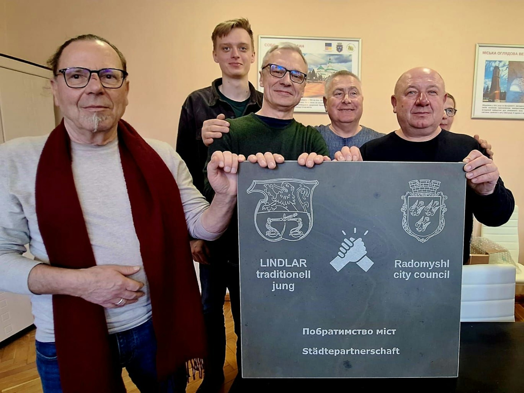 Das Foto zeigt Gäste und Gastgeber mit einer Grauwacketafel und einer zweisprachigen Aufschrift zur Städtepartnerschaft.