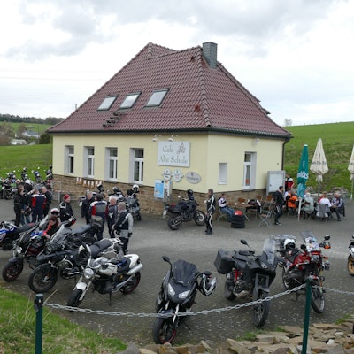 Viele Motorräder stehen auf dem Parkplatz vor einer Gaststätte.