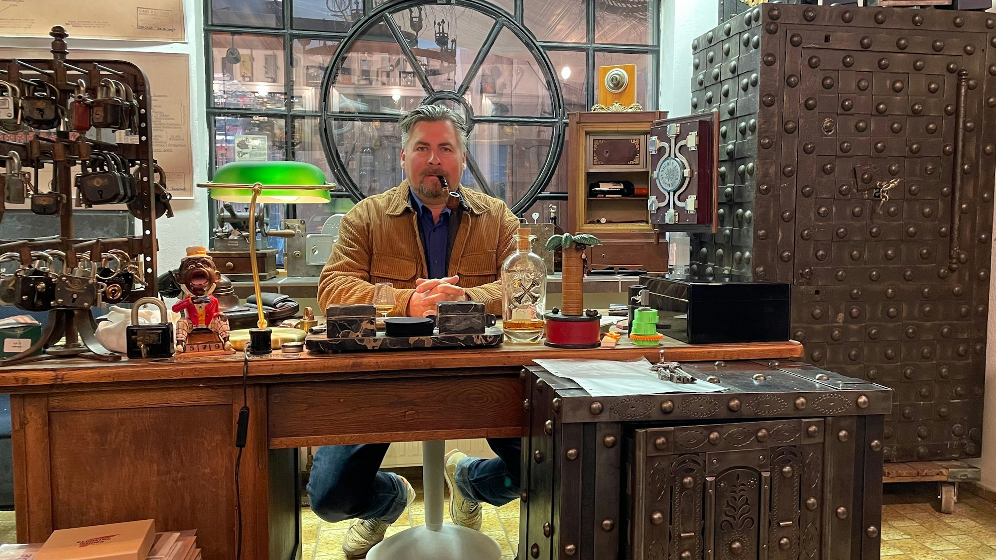 Lars Jelonnek sitzt hinterm Schreibtisch in seiner antiken Tresorsammlung