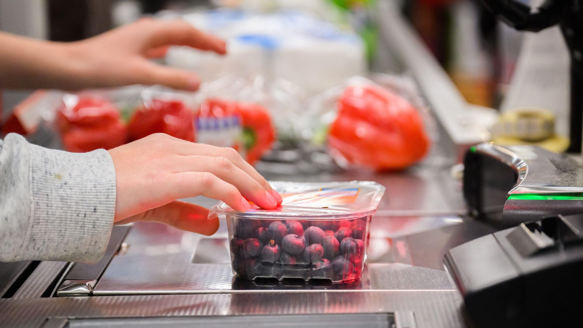 Eine Kassiererin scannt Heidelbeeren an der Kasse eines Supermarktes. (Symbolbild)