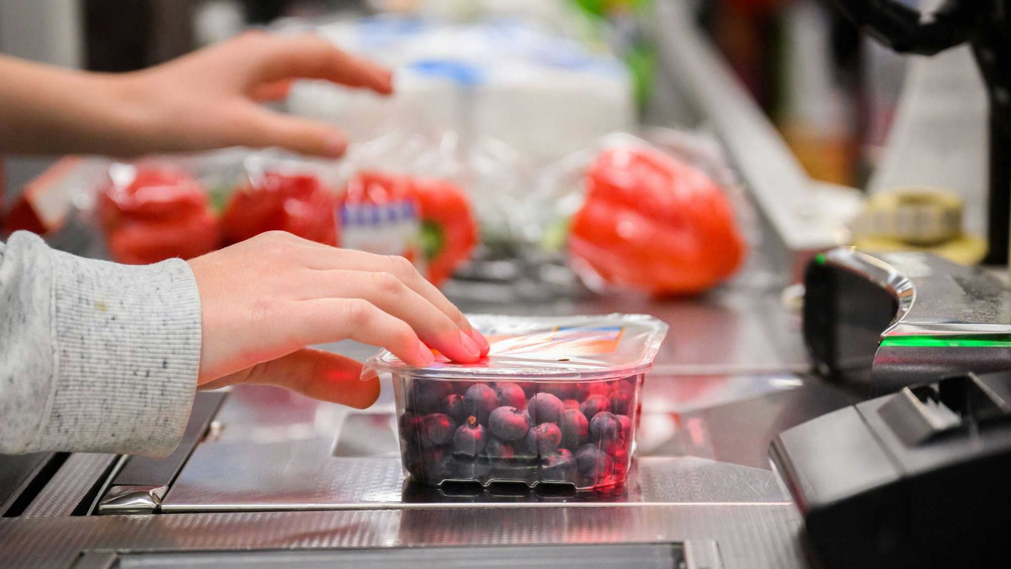 Eine Kassiererin scannt Heidelbeeren an der Kasse eines Supermarktes. (Symbolbild)