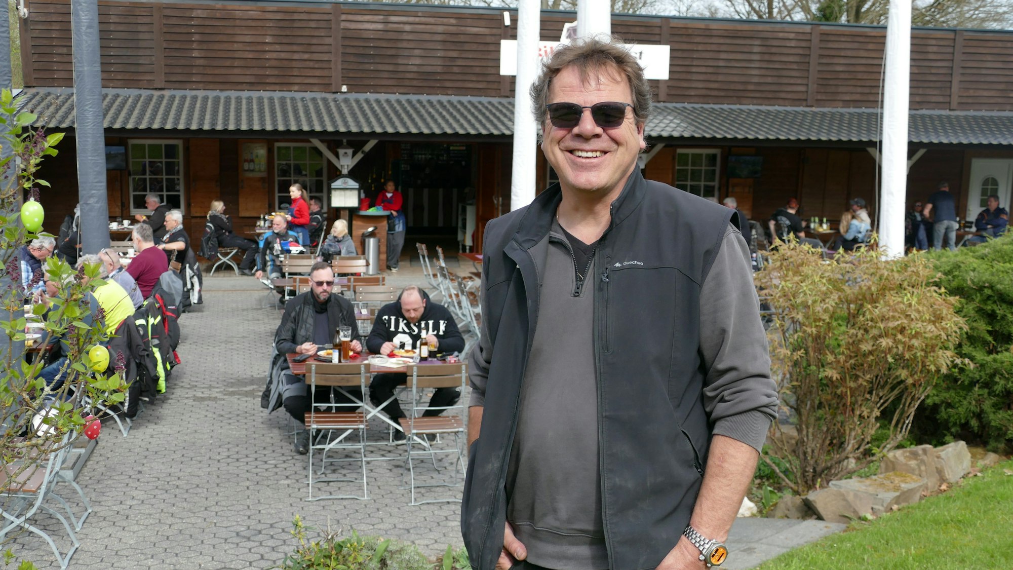 Ein Mann mit Sonnenbrille grinst in die Kamera.