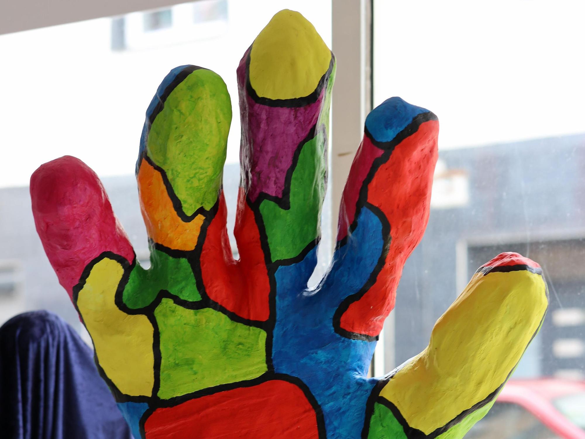 Eine große Hand-Skulptur ist bunt bemalt.