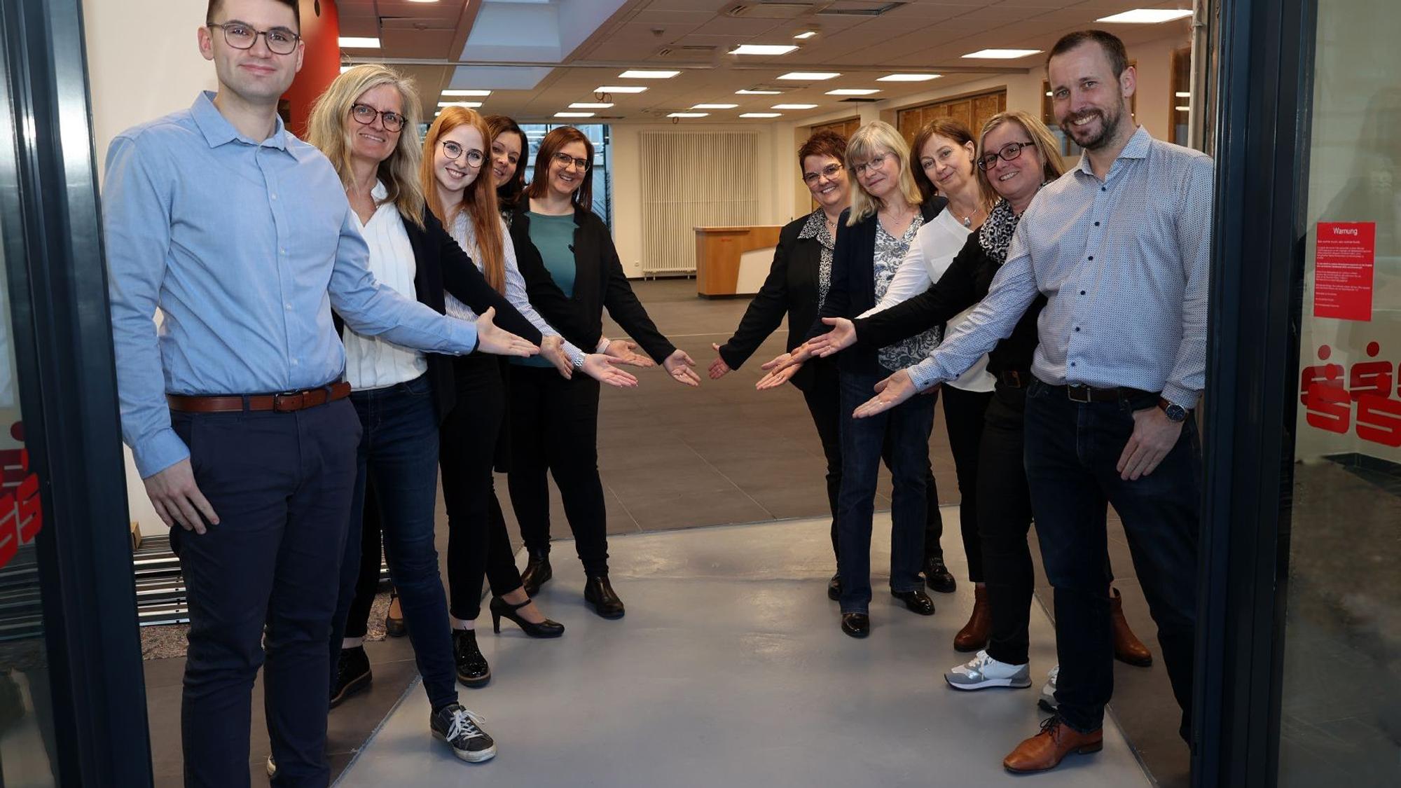 Mitarbeiter der Kreissparkasse Euskirchen stehen hinter dem Eingang Spalier und weisen den Weg ins Beratungscenter.
