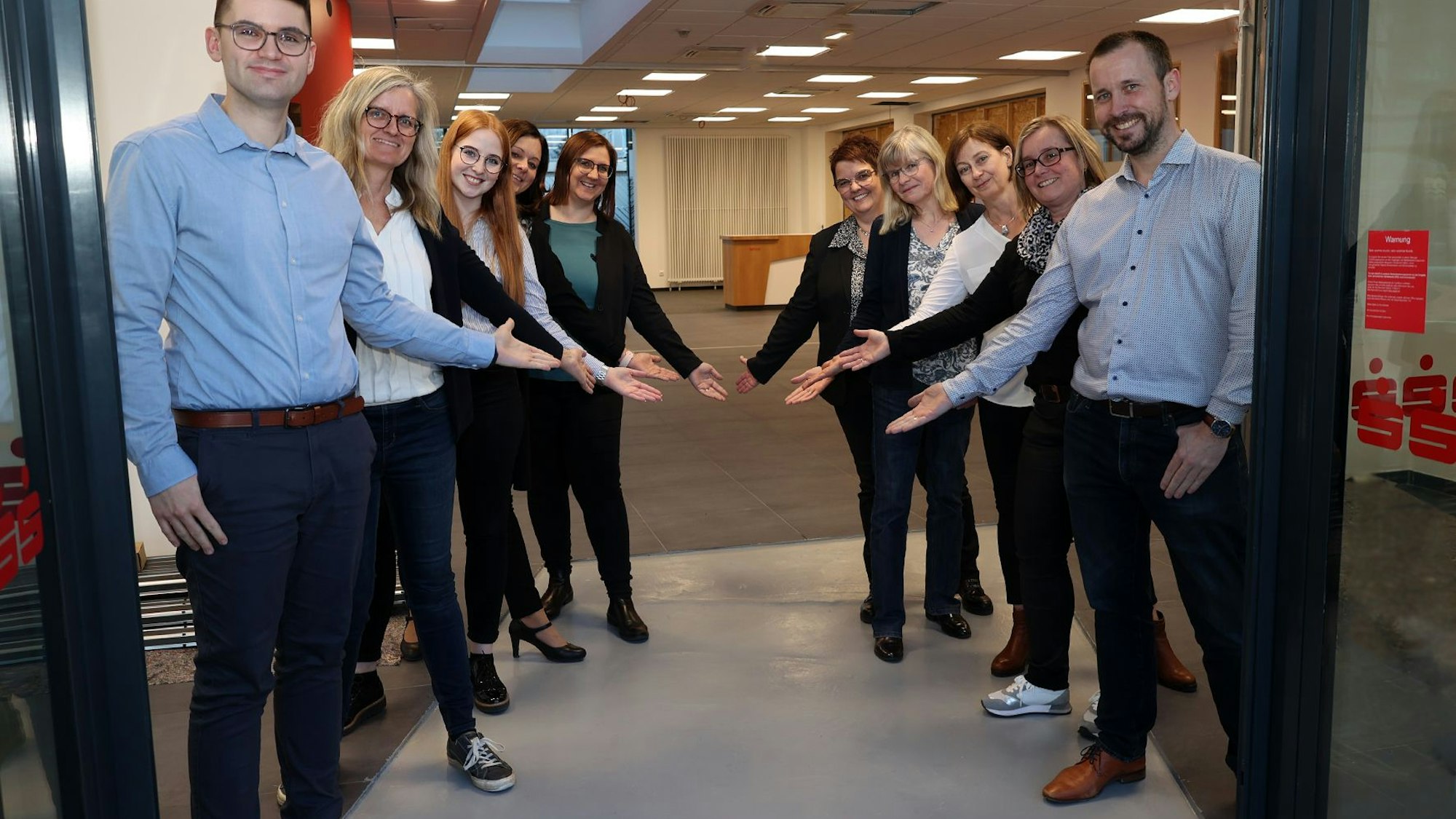 Mitarbeiter der Kreissparkasse Euskirchen stehen hinter dem Eingang Spalier und weisen den Weg ins Beratungscenter.