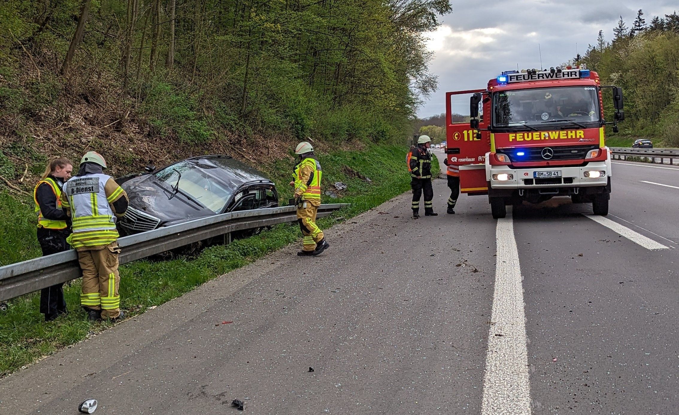 Zwei Personen haben sich bei einem Autounfall auf der A553 in Brühl verletzt. Feuerwehrleute sind an der Unfallaufnahmestelle zu sehen.