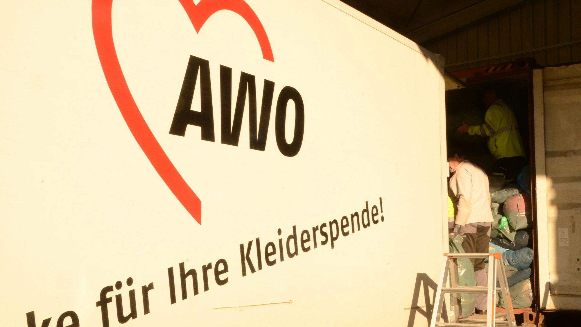 Seitenansicht eines Lastwagens. In einem roten Herz ist die Abkürzung AWO zu lesen, darunter „danke für Ihre Kleiderspende“.