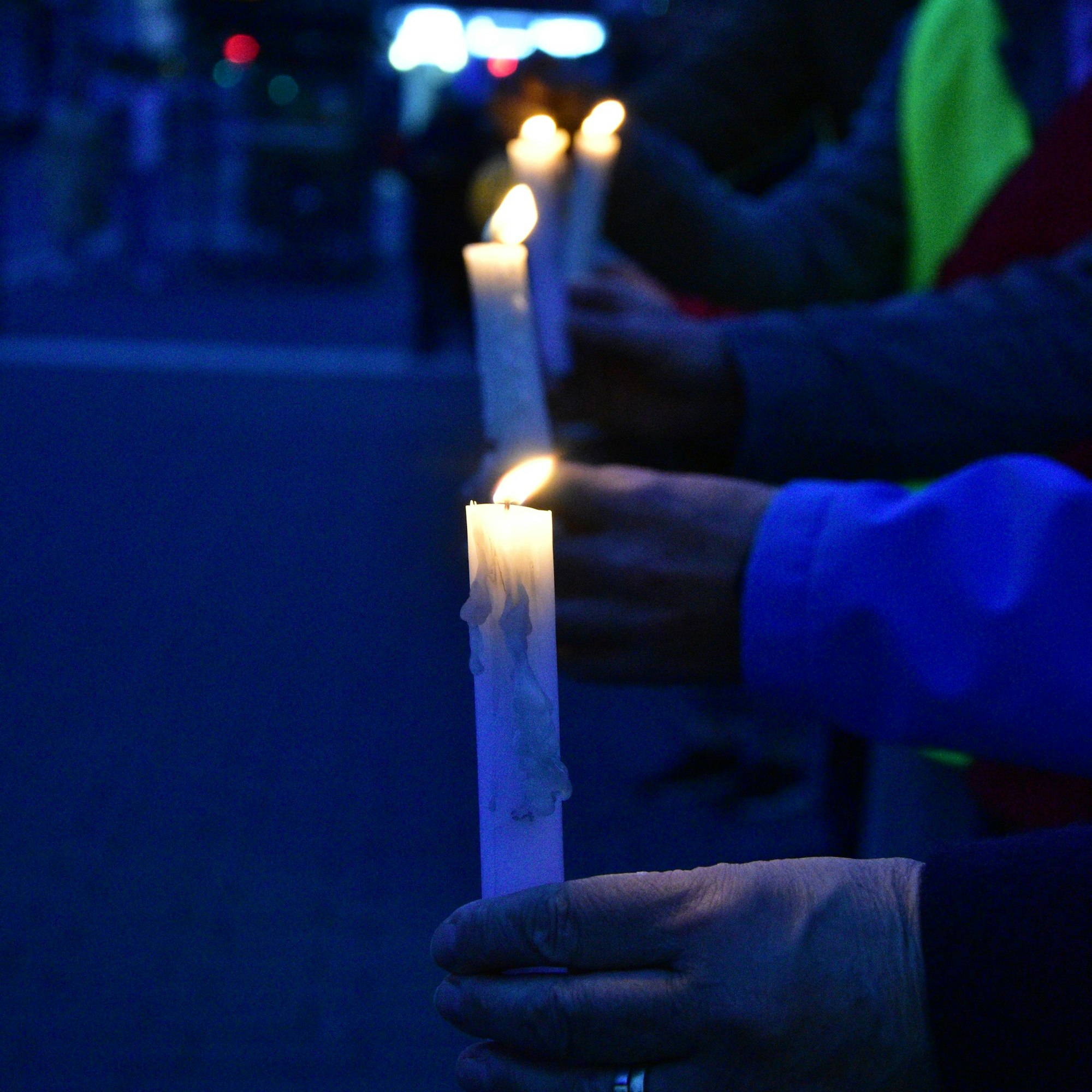 Hände halten brennende Kerzen.
