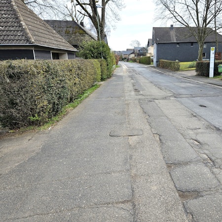 Blick auf die Ortsdurchfahrt mit der mehrfach geflickten Straße.