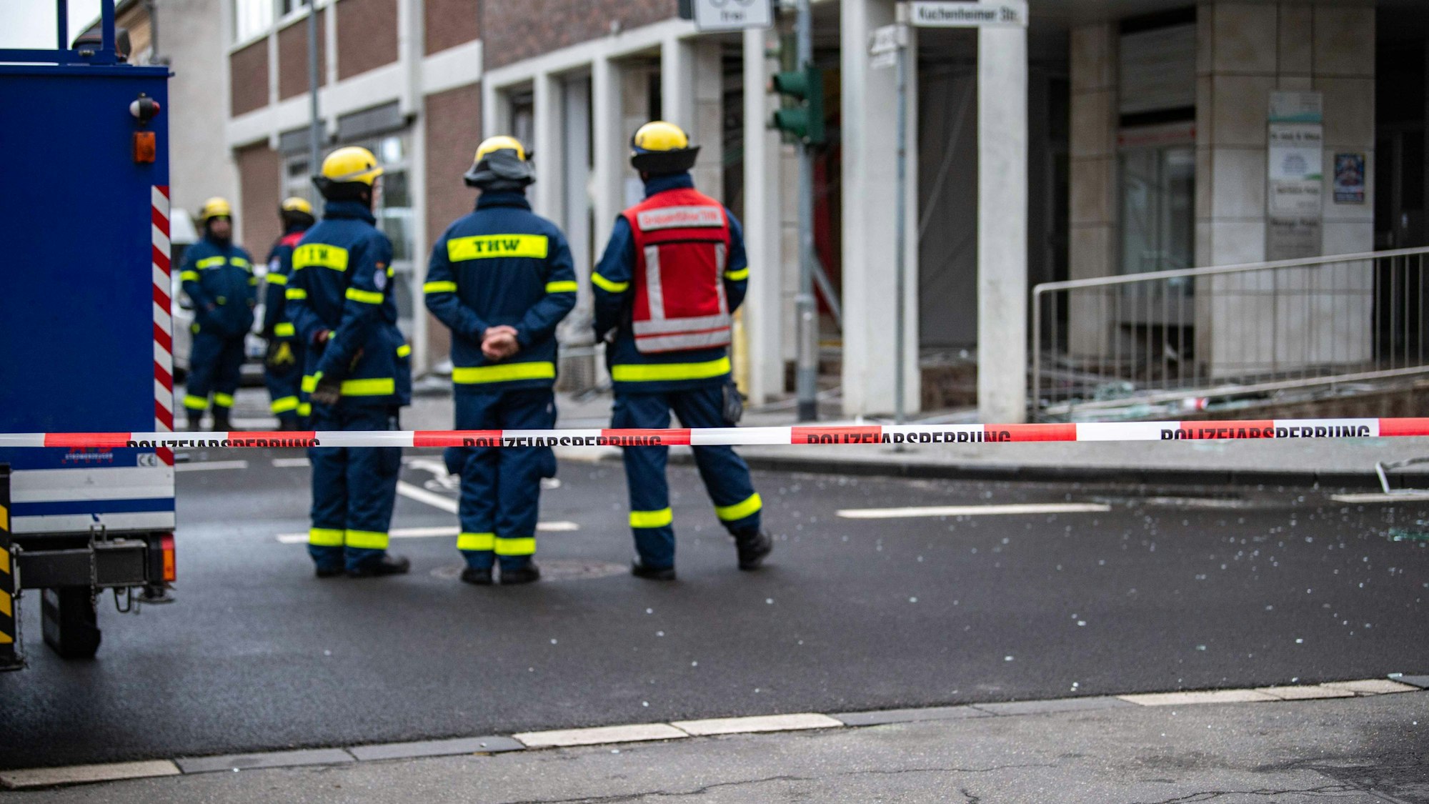Das Bild zeigt Einsatzkräfte des Technischen Hilfswerks in Kuchenheim. Sie stehen hinter einer Absperrung.