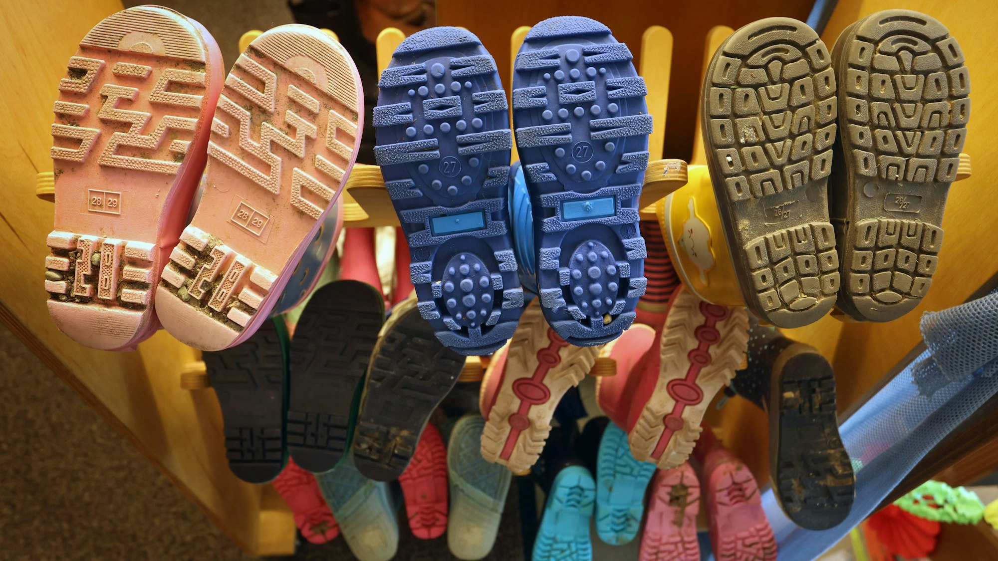 Gummistiefel von Kindern an einem Gestell aufgereiht.