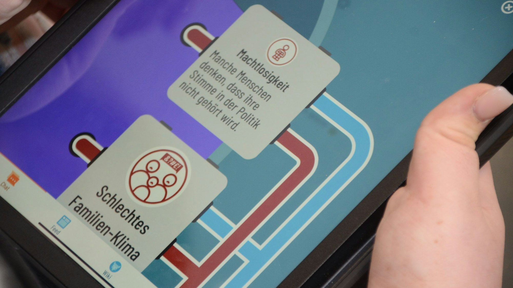 Der Bildschirm eines Tablets. Zu sehen sind Sprechblasen mit Begriffen wie Machtlosigkeit und Schlechtes Familien-Klima.