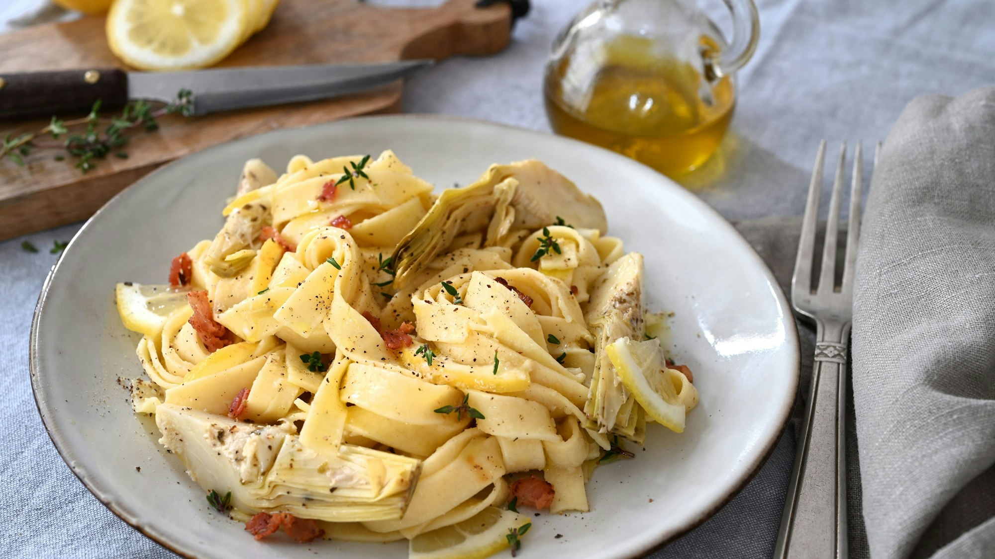 Neben der cremigen Artischockensoße machen auch gegrillte Artischockenherzen, knuspriger Bauchspeck und süßliche Zitrusnoten aus einfachen Bandnudeln einen herzhaften Pastaschmaus.