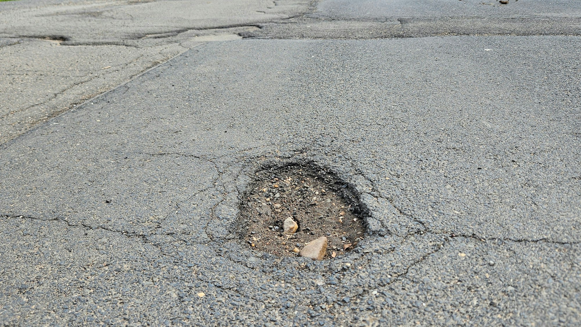 Das Foto zeigt ein Loch im Asphalt in der Ortsdurchfahrt von Herhahn.