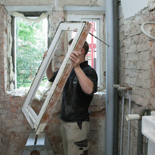 Ein Mann baut ein Fenster aus einem alten Haus aus.