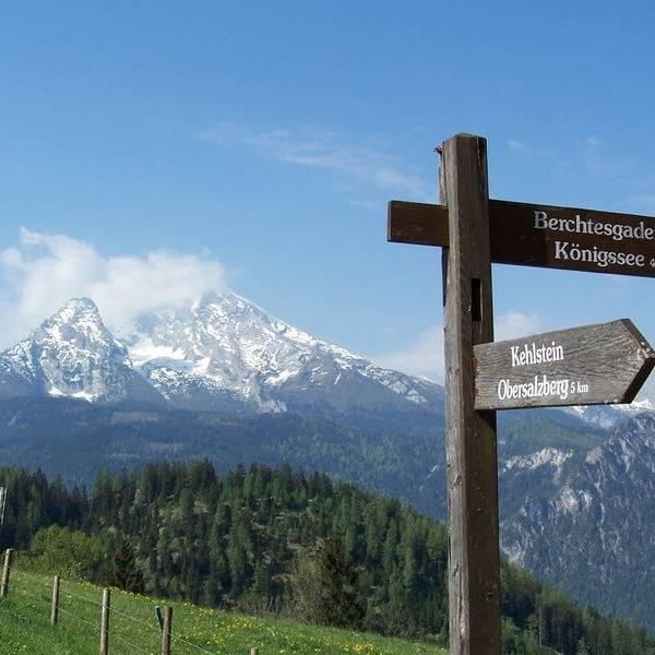 Ein Wegweiser steht vor den Berchtesgadener Alpen.