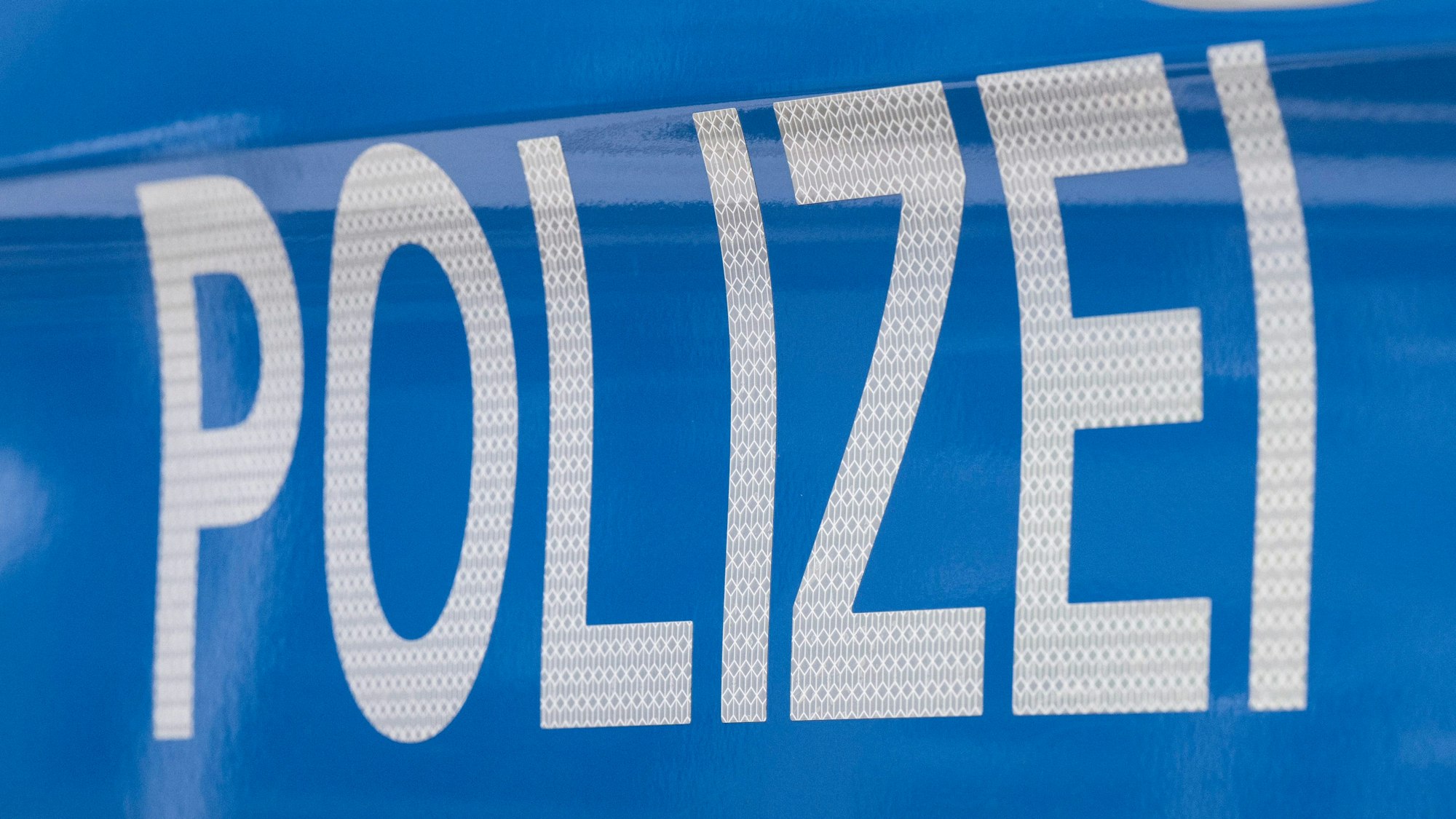 Der Schriftzug ·Polizei· ist auf einem Streifenwagen zu lesen.