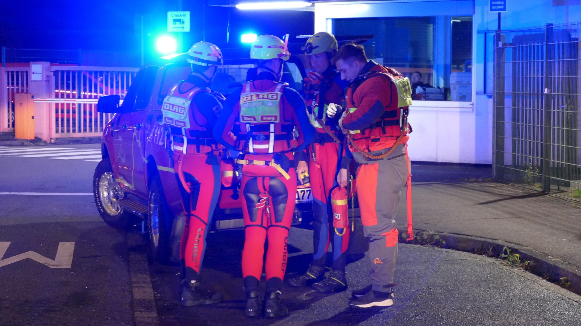 Menschen in Neoprenanzügen stehen an einem Fahrzeug.