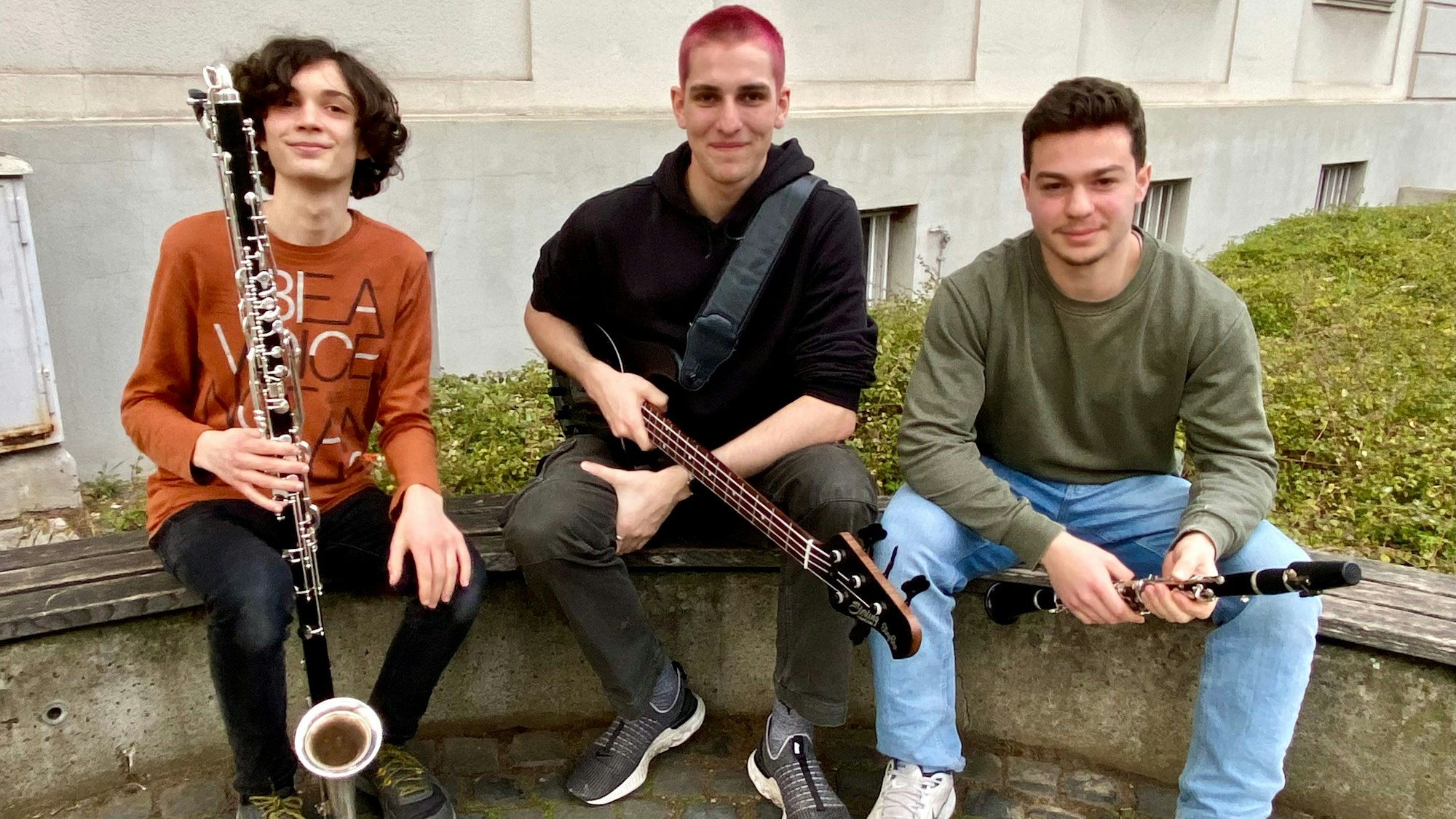 Zu sehen sind drei junge Musiker mit ihren Instrumenten.