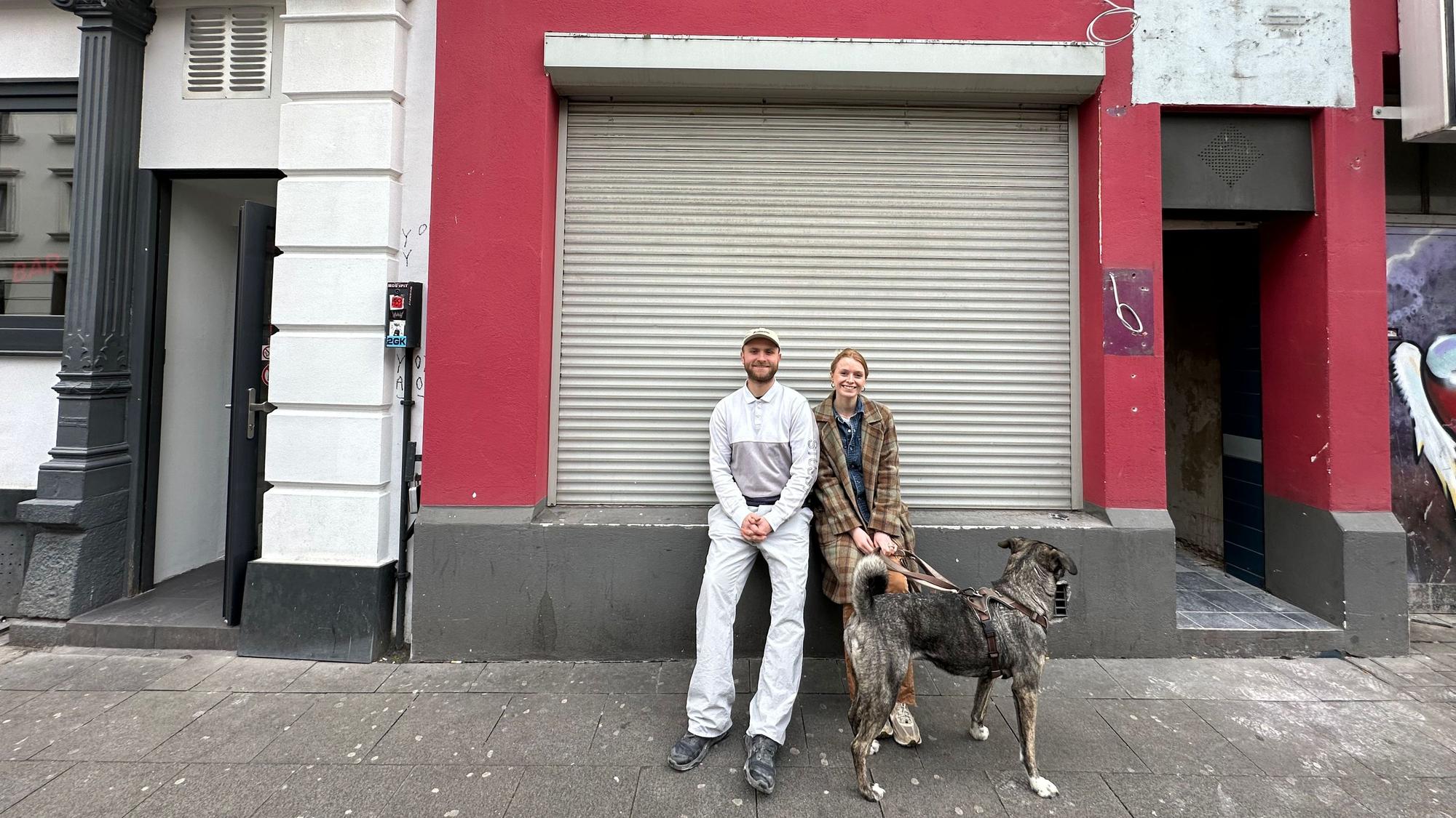 Pauline Schmeling und Johannes Ipfelkofer sitzen vor einem Ladenlokal.