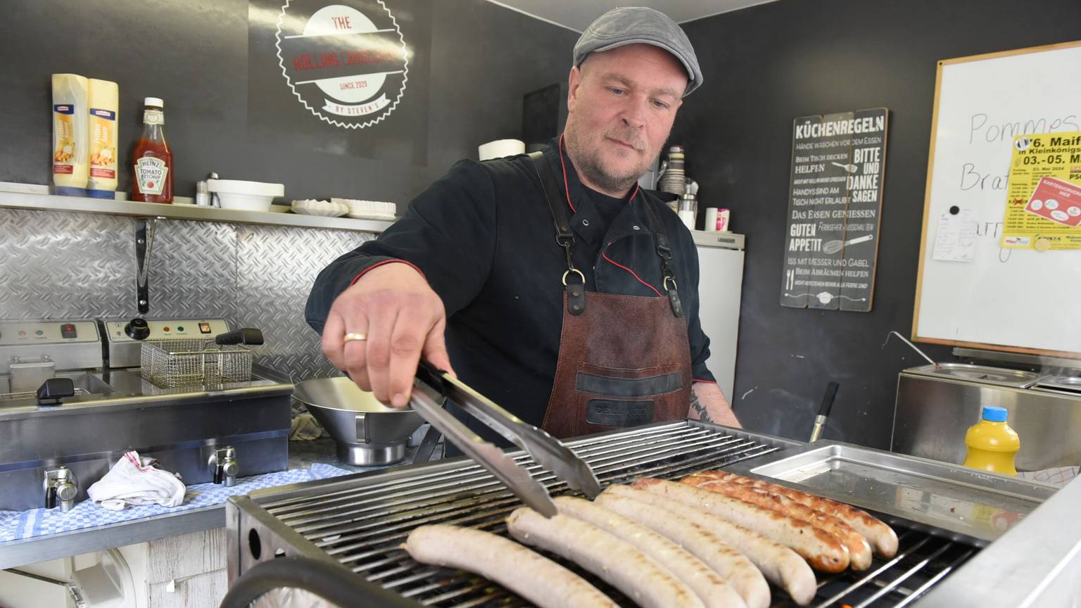 Der gelernte Metzger legt Würste auf den Grill.