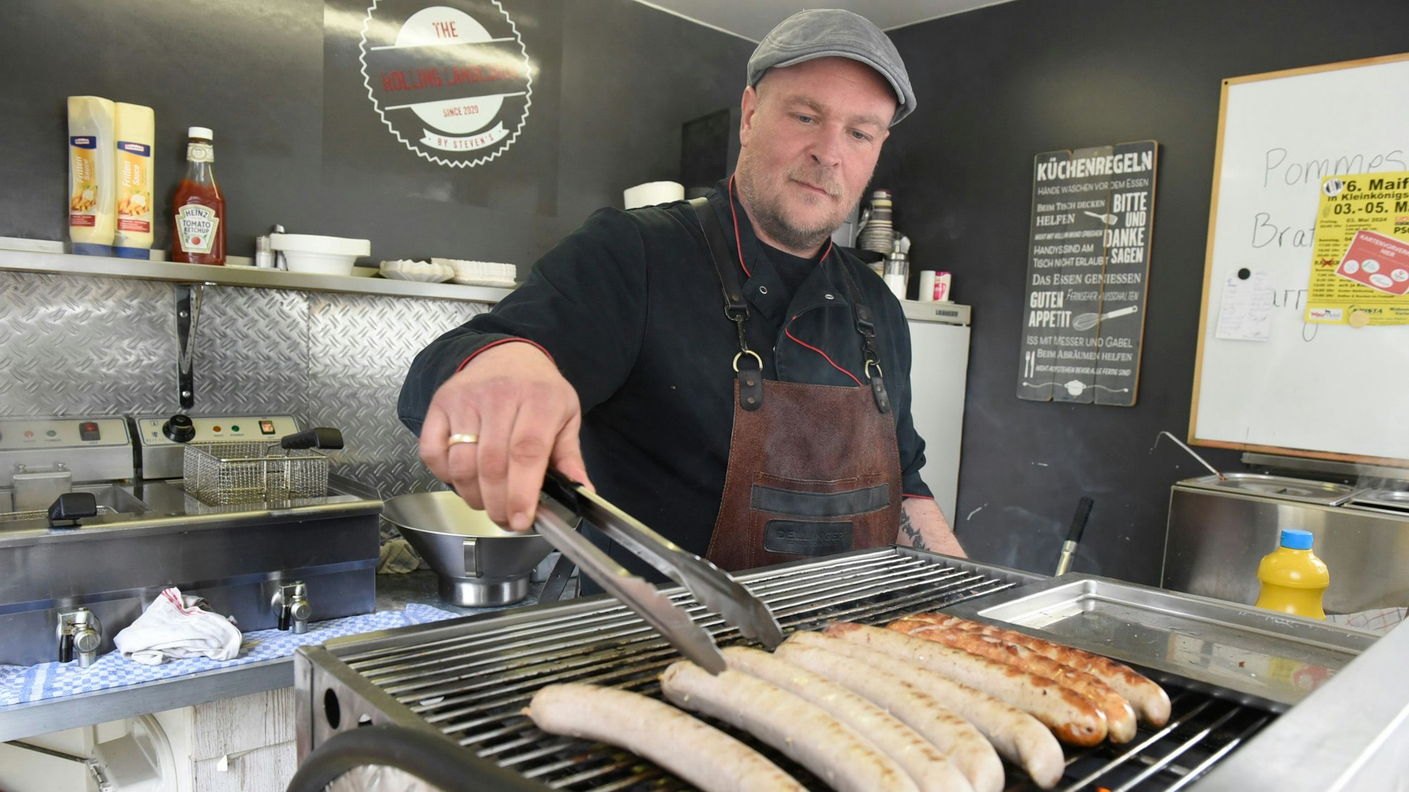 Der gelernte Metzger legt Würste auf den Grill.