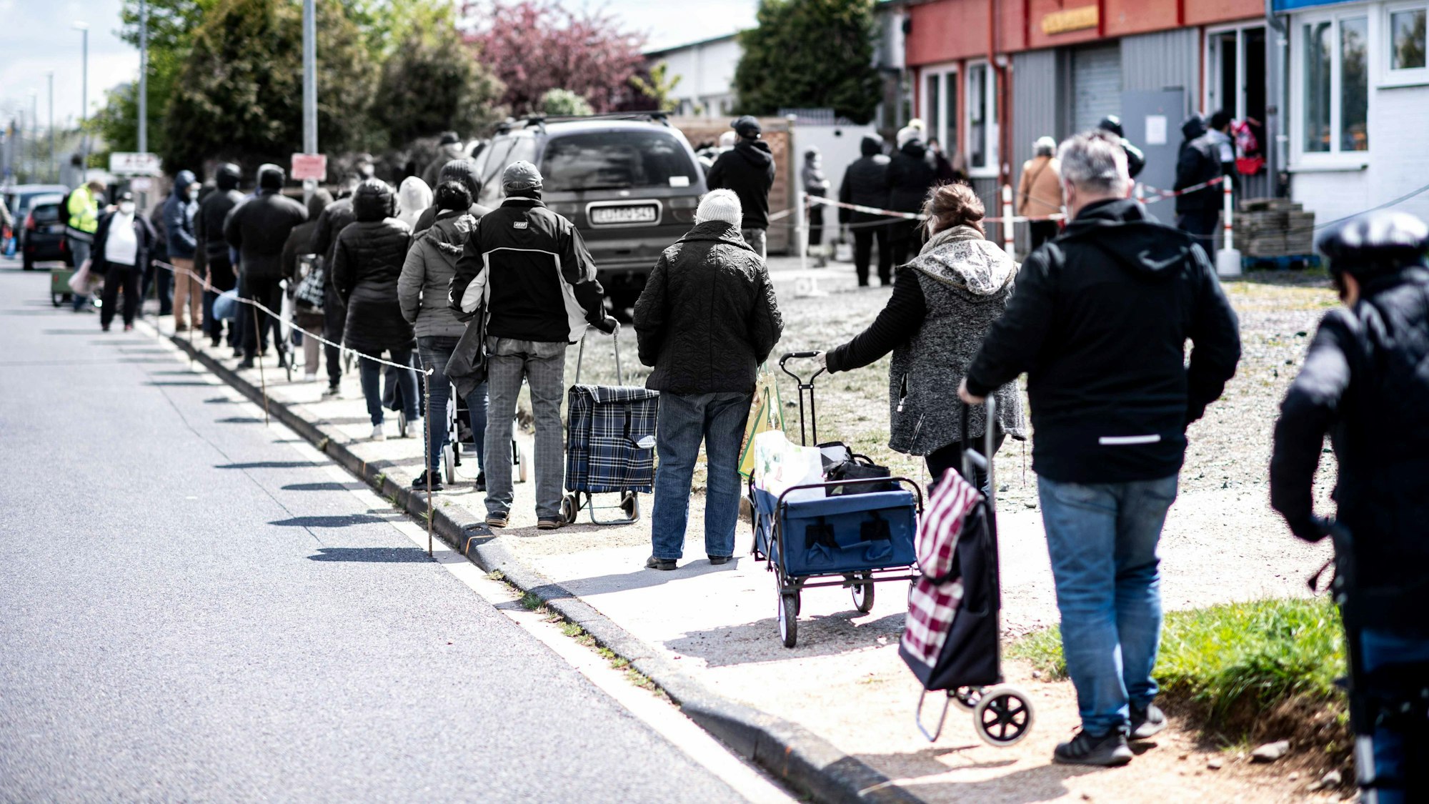 Das Bild zeigt eine Menschenschlange vor der Euskirchener Tafel, die auf die Ausgabe der Lebensmittel wartet.