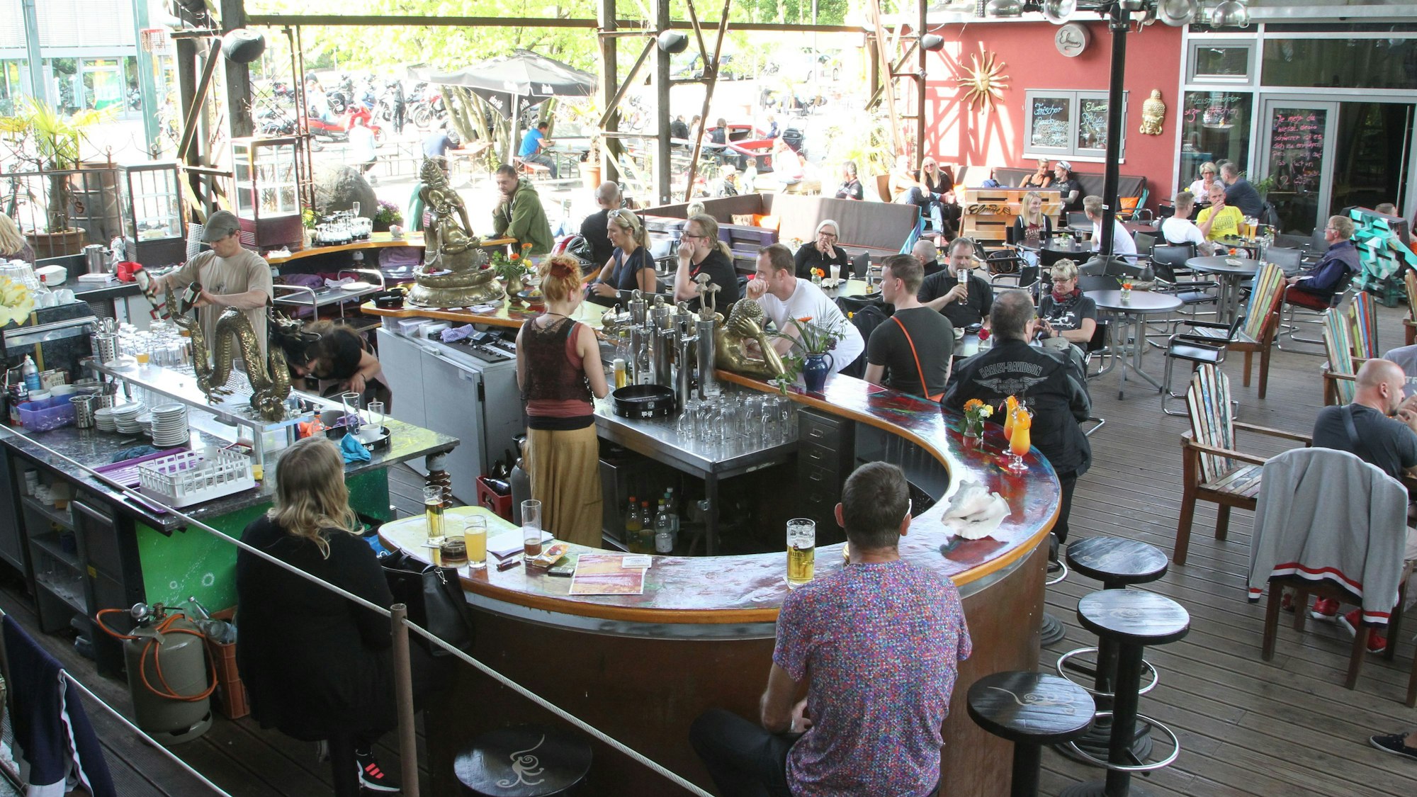 Hinter einer halbrunden Theke schenken Menschen Getränke aus.