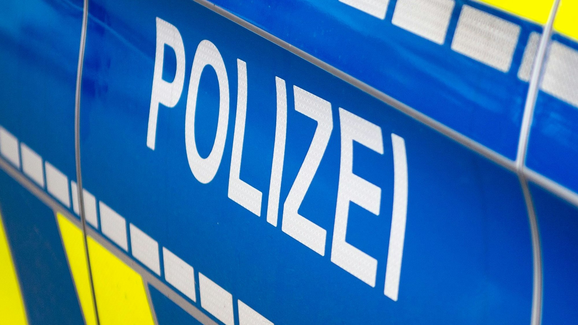 Das Symbolfoto zeigt die Tür eines Streifenwagens, auf dem auf blauem Hintergrund der Schriftzug „Polizei“ steht.