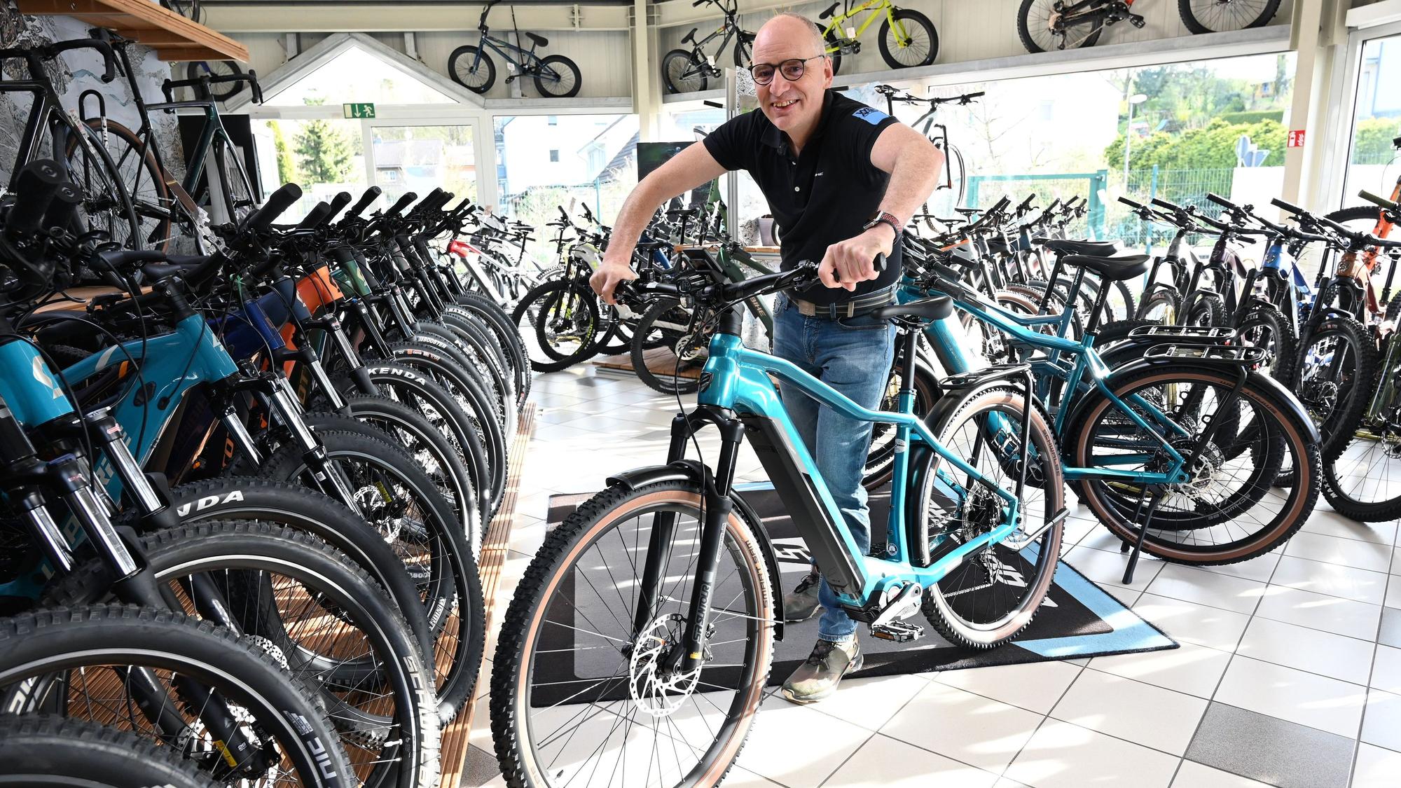 Ein Mann steht mit einem E-Bike in einem Fahrradladen.