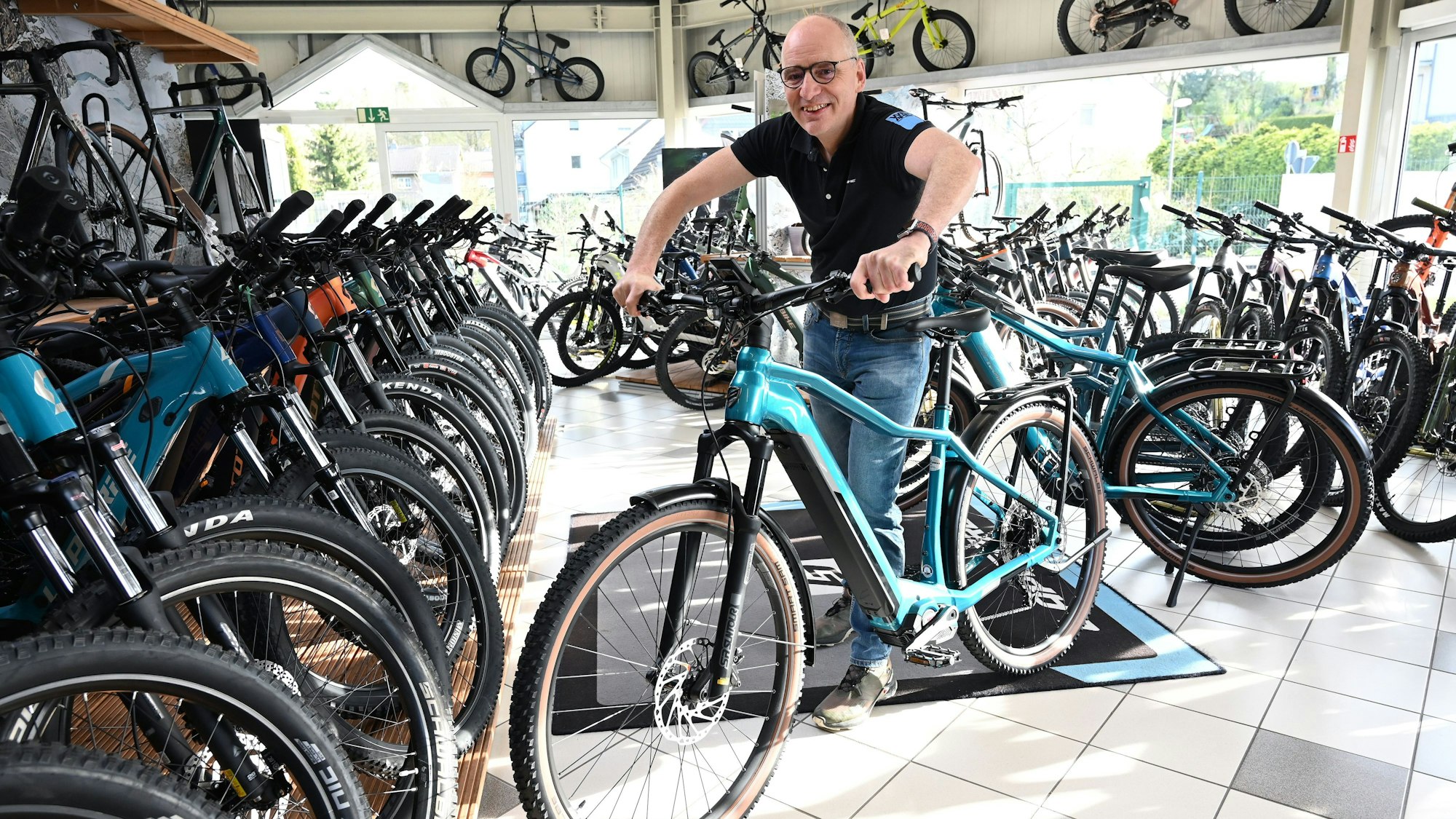 Ein Mann steht mit einem E-Bike in einem Fahrradladen.