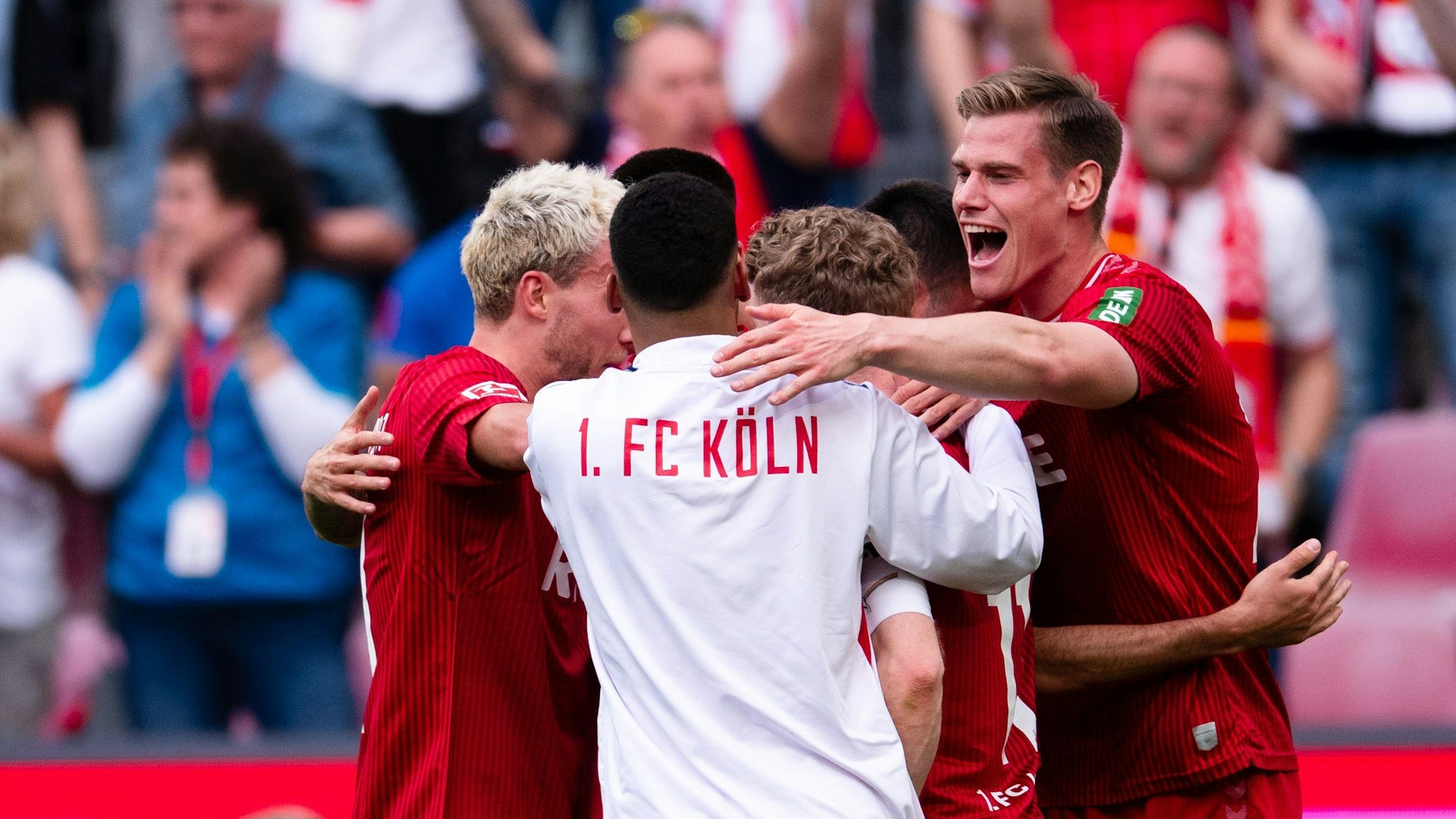 Die Spieler stehen in einem Kreis, jubeln und umarmen sich.