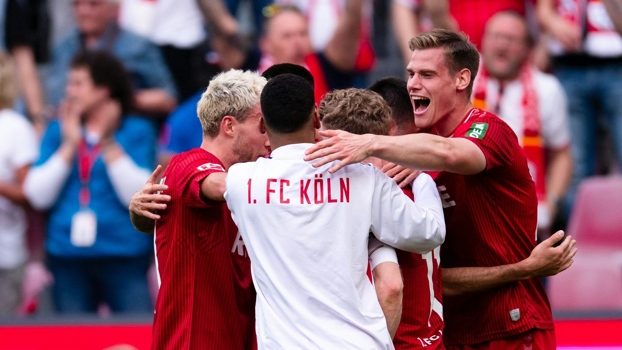 Die Spieler stehen in einem Kreis, jubeln und umarmen sich.