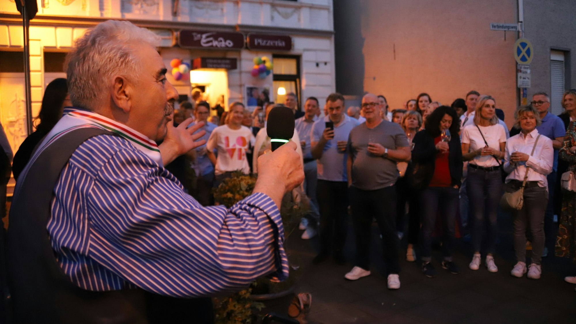 Ein Mann mit Mikrofon steht vor dem Restaurant „Da Enzo“ an der Kaiserstraße in Siegburg.