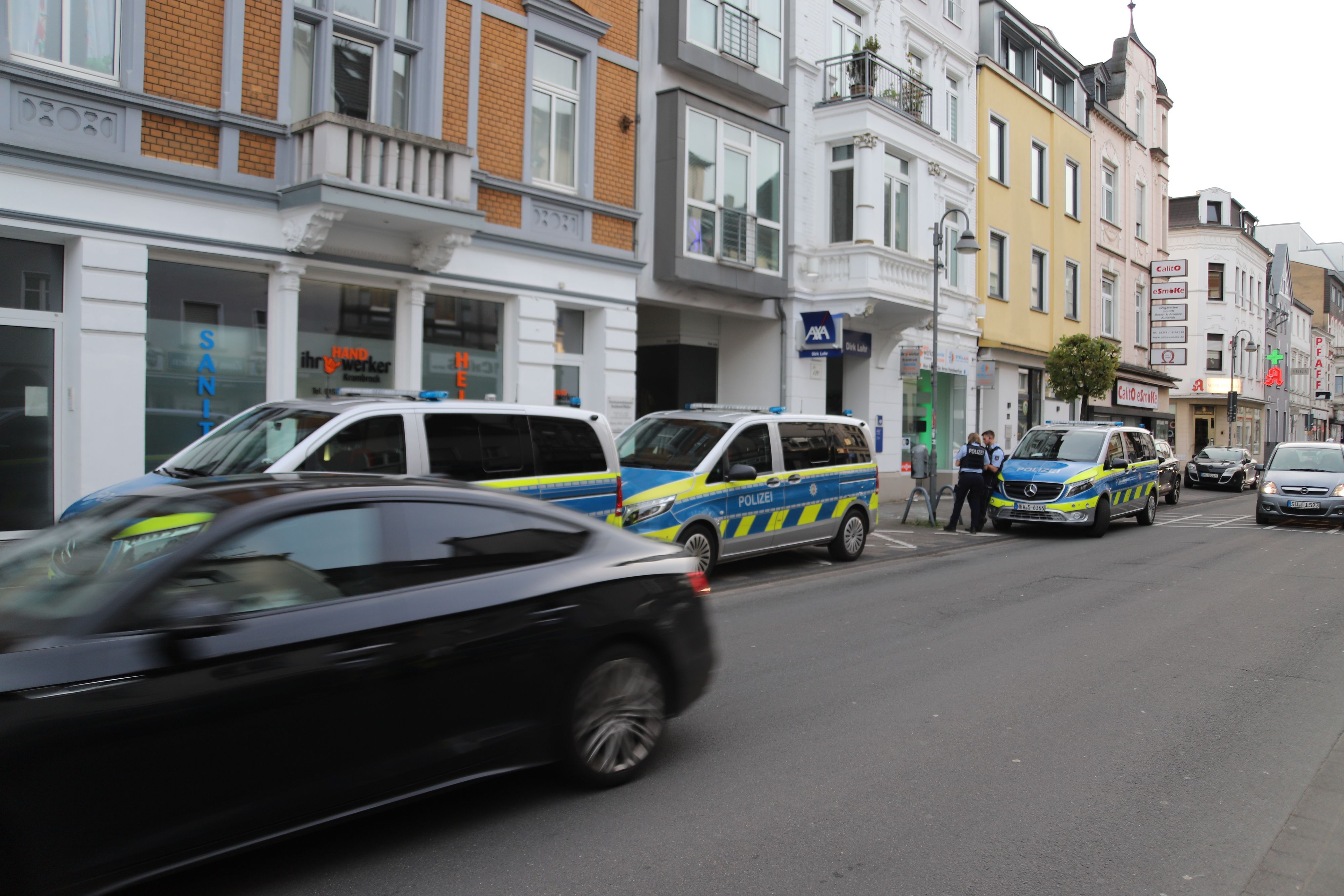 Mehrere Fahrzeuge der Polizei stehen vor einer Häuserzeile.