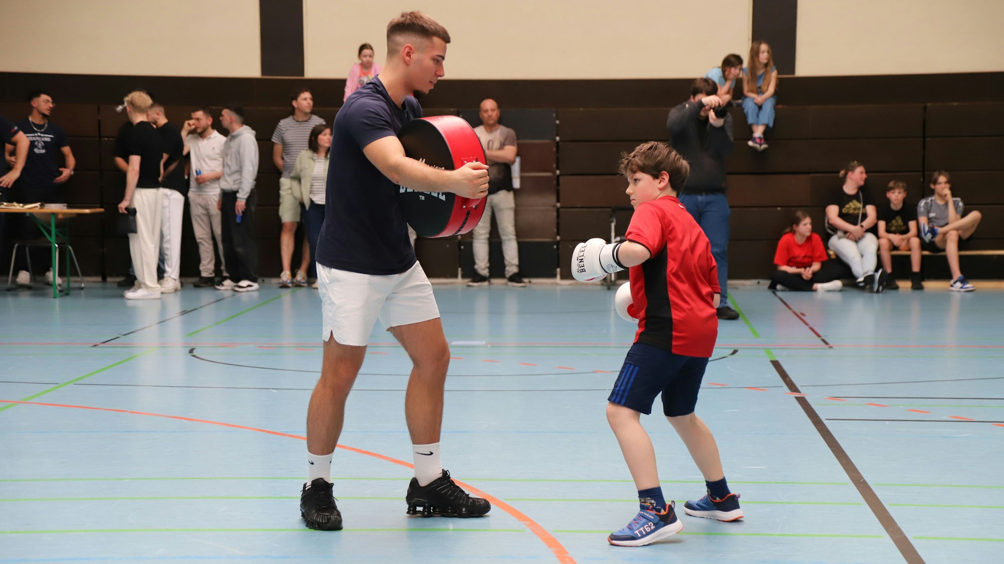 Ein Junge in Sportkleidung und ein Jugendlicher beim Boxtraining.