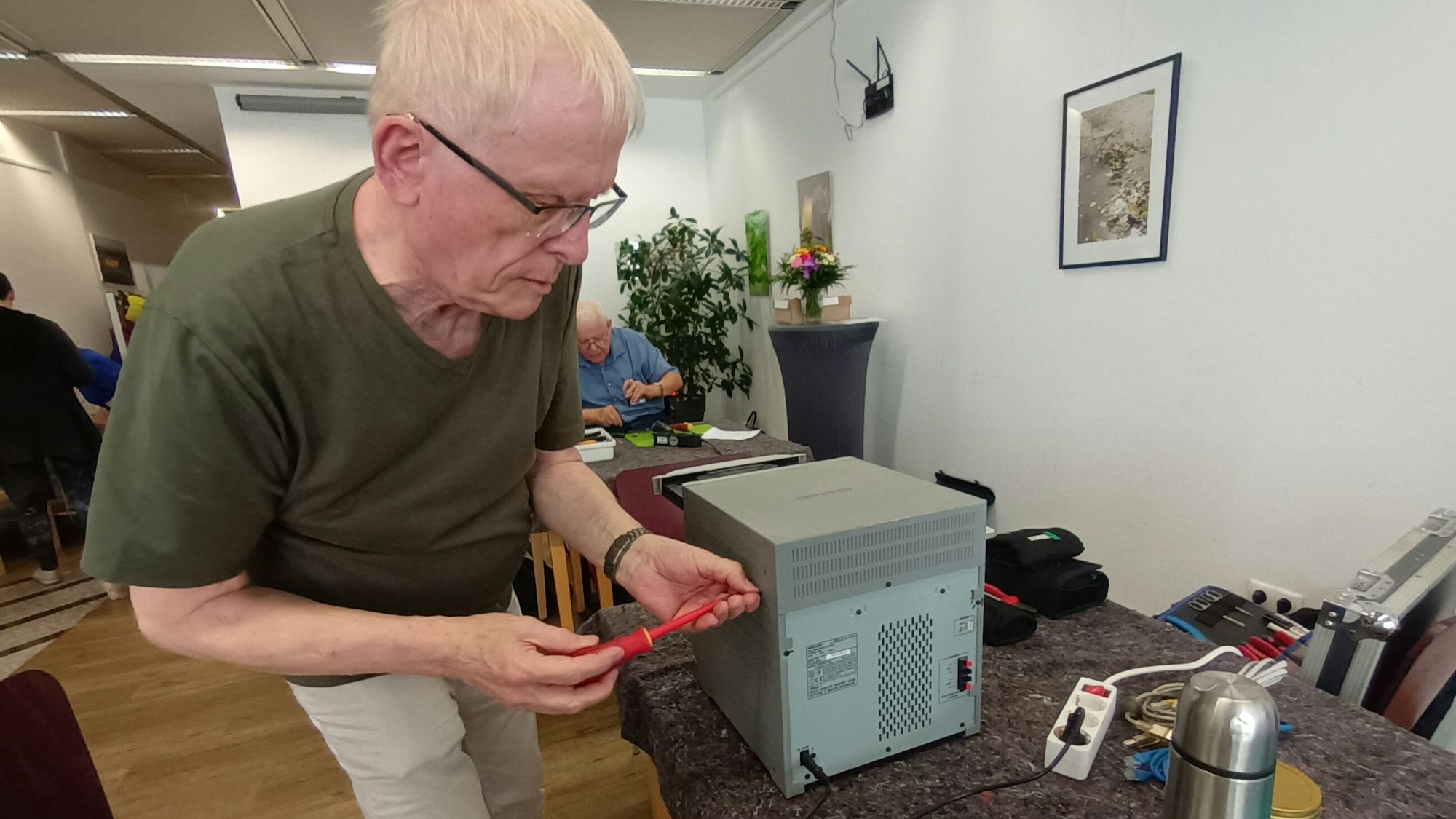 Ein Mann mit Brille schraubt an einem CD-Player.