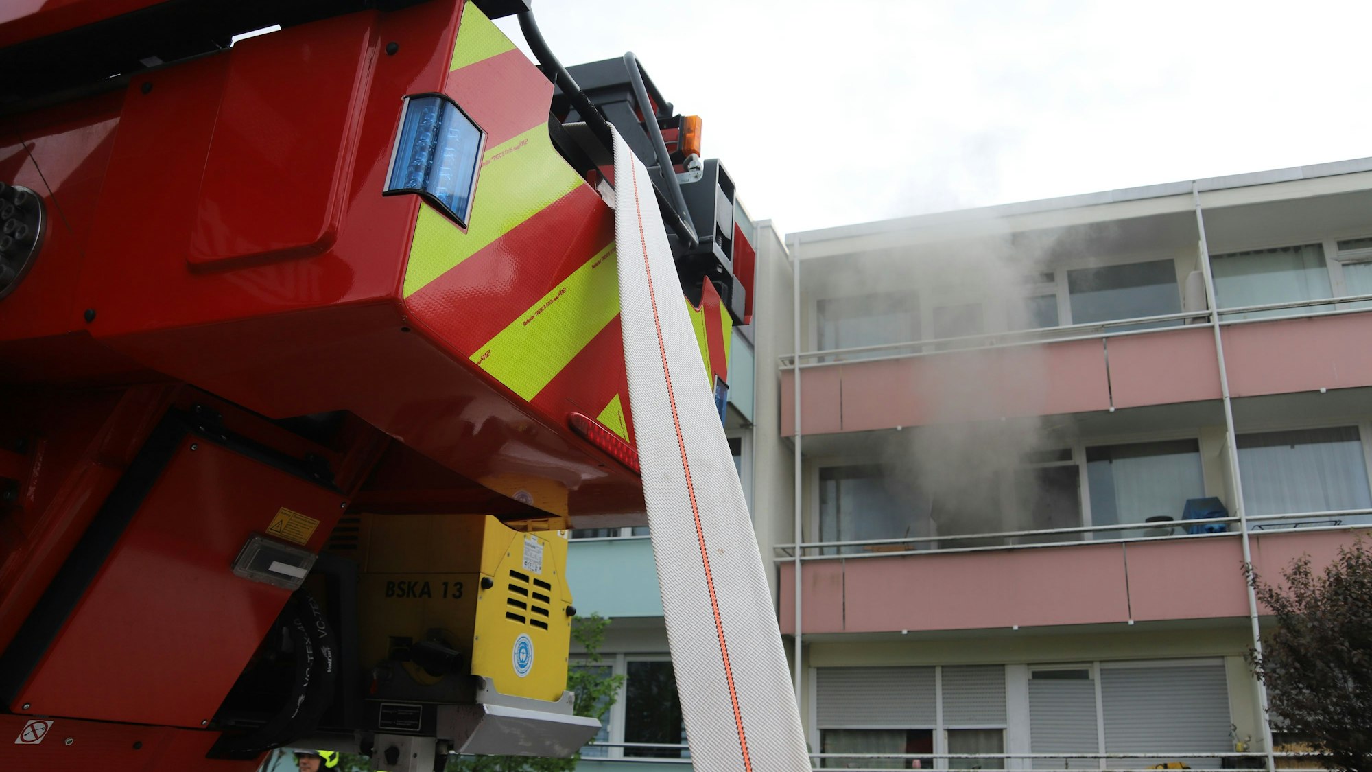 In Sankt Augustin-Hangelar hat ein Schrank in einem Zimmer gebrannt. Das Haus wurde geräumt, die Wohnung ist unbewohnbar. Rauch zieht aus dem Fenster des betroffenen Zimmers ins Freie.