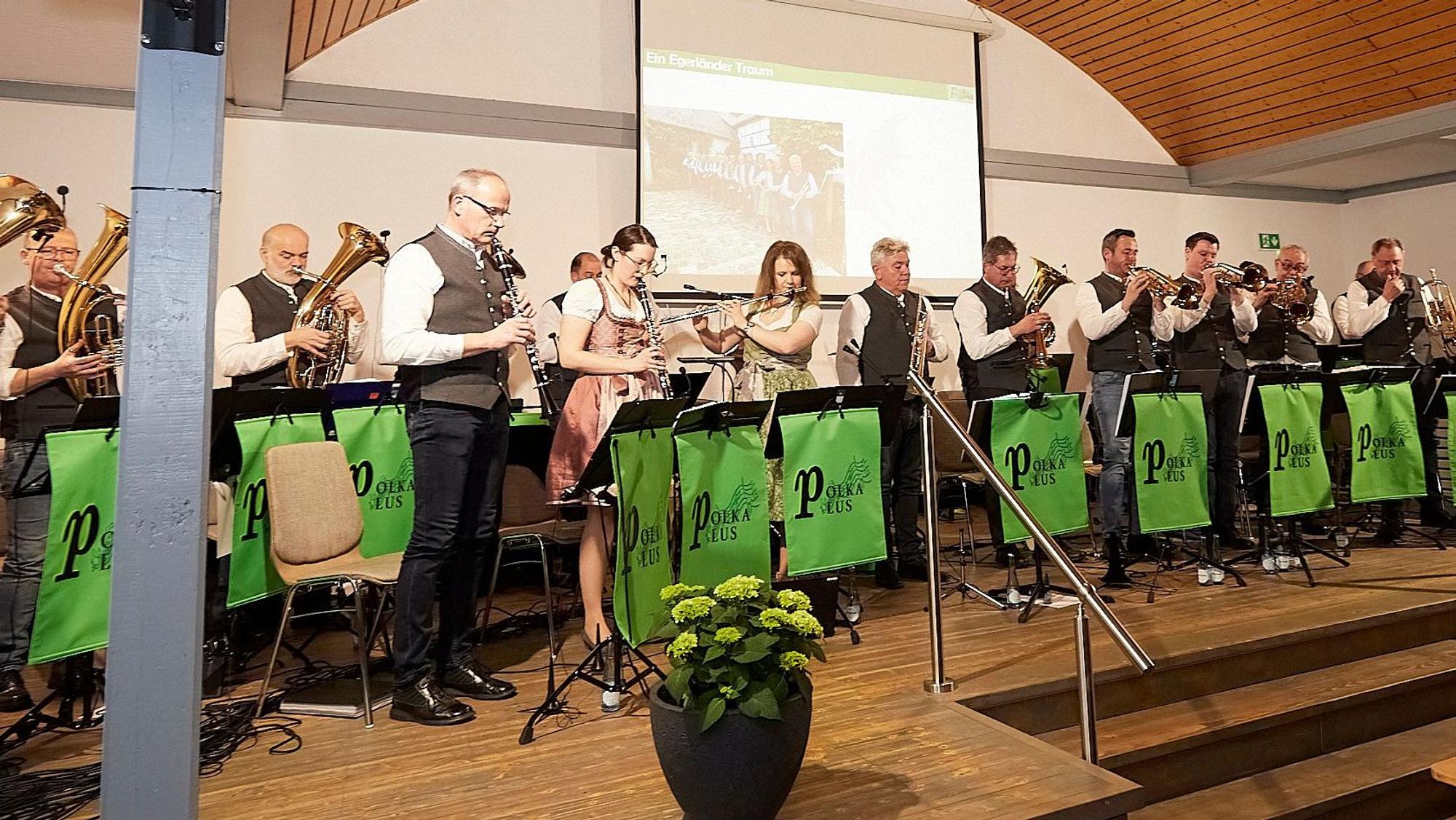Das „Polka Plus“-Ensemble steht auf der Bühne und spielt auf Blasinstrumenten.
